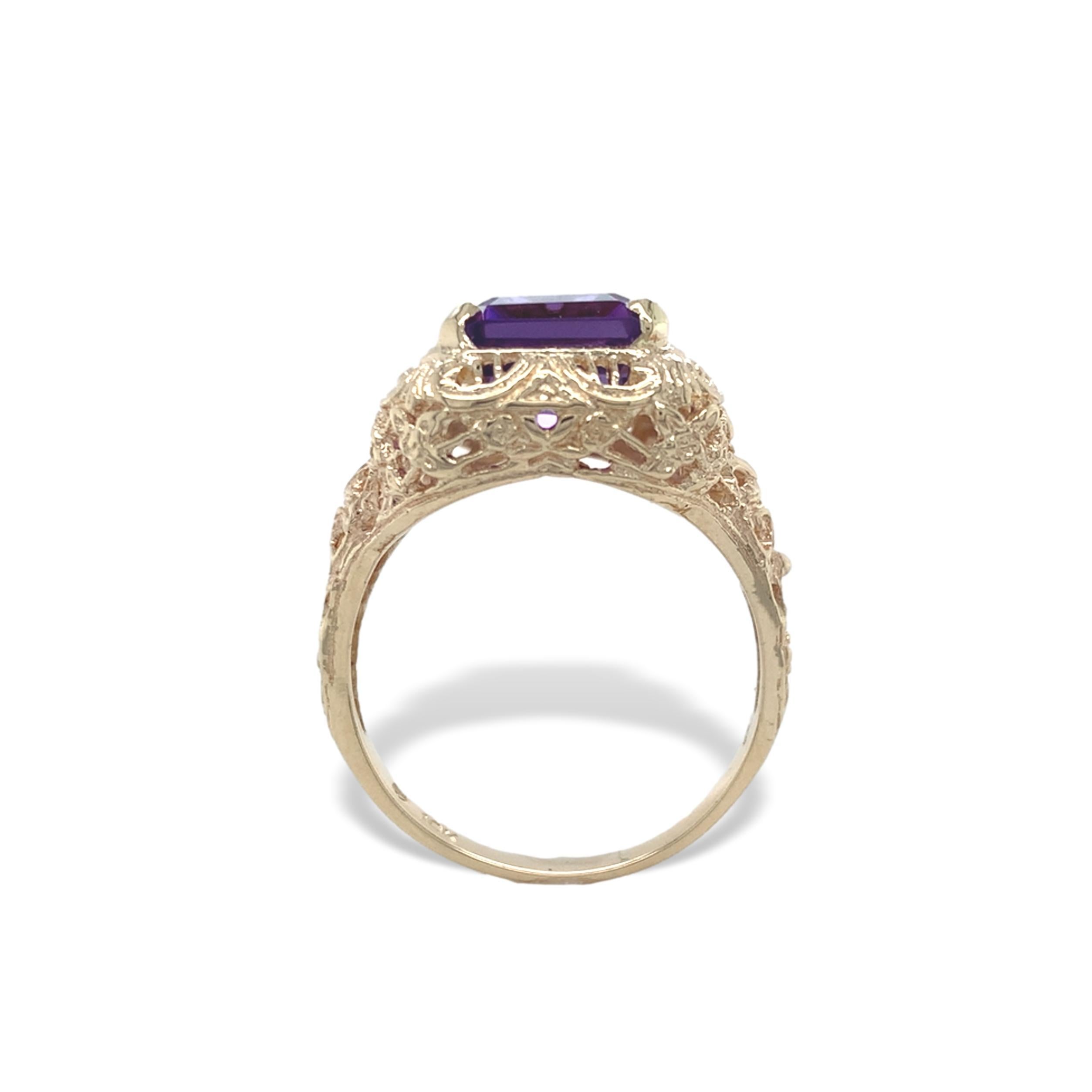 Bague filigrane en or jaune 10K avec améthyste. L'améthyste authentique extraite de la terre est de taille émeraude et mesure environ 11 mm x 9 mm pour un poids de 4,38 carats. L'améthyste est de couleur violet moyen. La bague convient à un doigt de