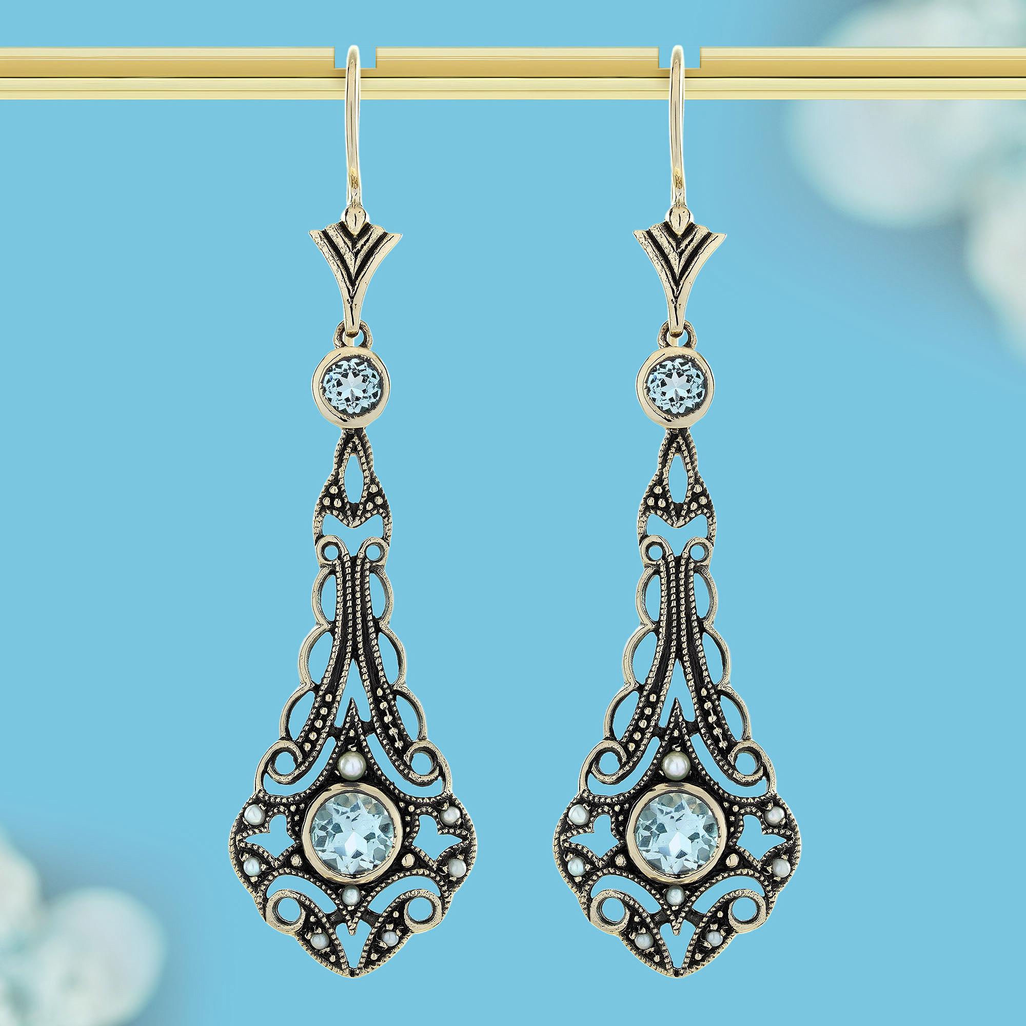 Exuding vintage charm, these exquisite earrings showcase radiant blue topaz gems nestled within intricate filigree work, a delicate lace of artistry that frames their brilliant sparkle. Surrounding each stone, soft pearls add a timeless glow,