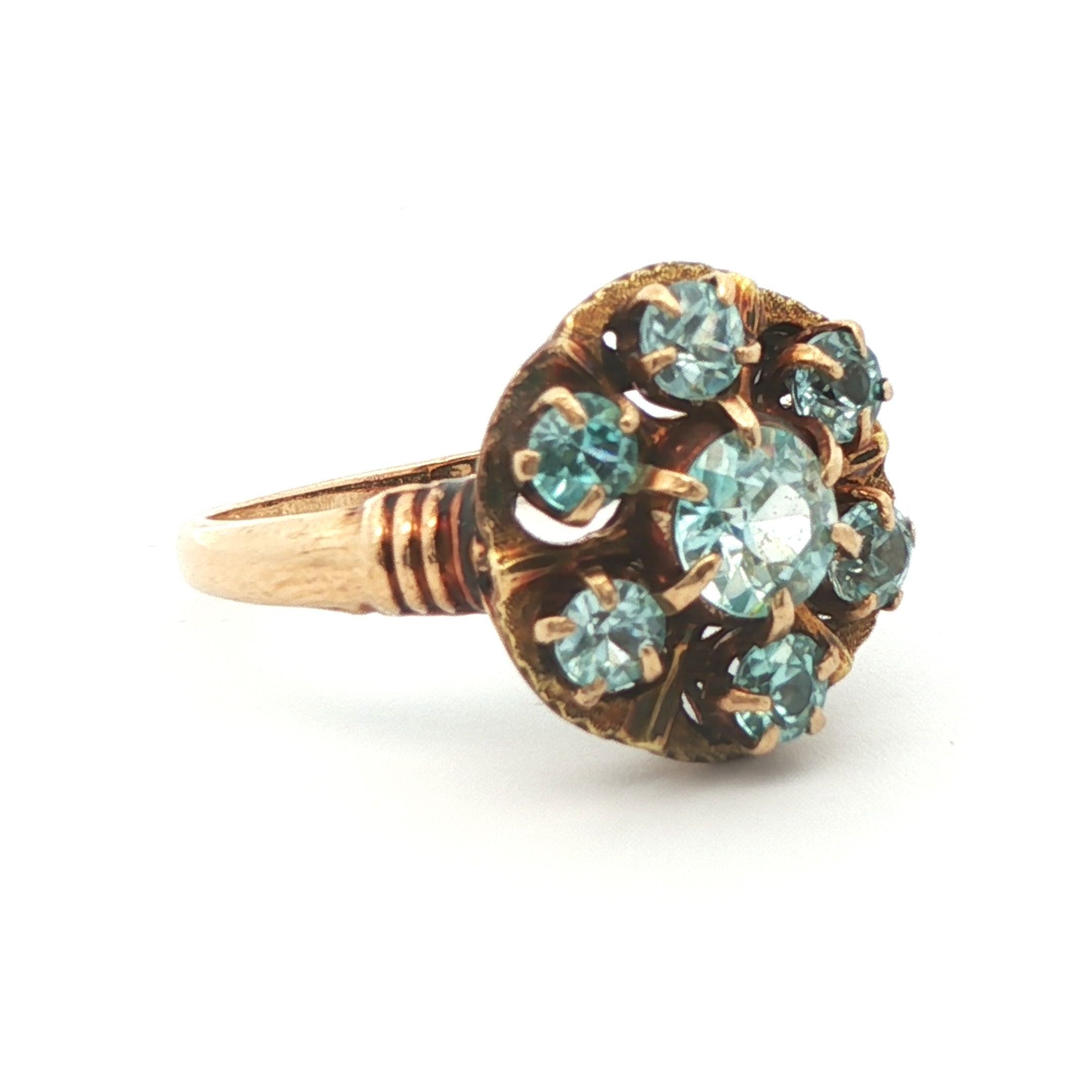 Diese Kiefer fallen Zirkon Cluster Ring stammt aus der 1890 viktorianischen Zeit und wurde in 10k Gelbgold gemacht. Der Kopf des Rings ist kreisförmig und zeigt eine große Ansammlung von leuchtend blauen Zirkonen. Der Diamant in der Mitte ist ein