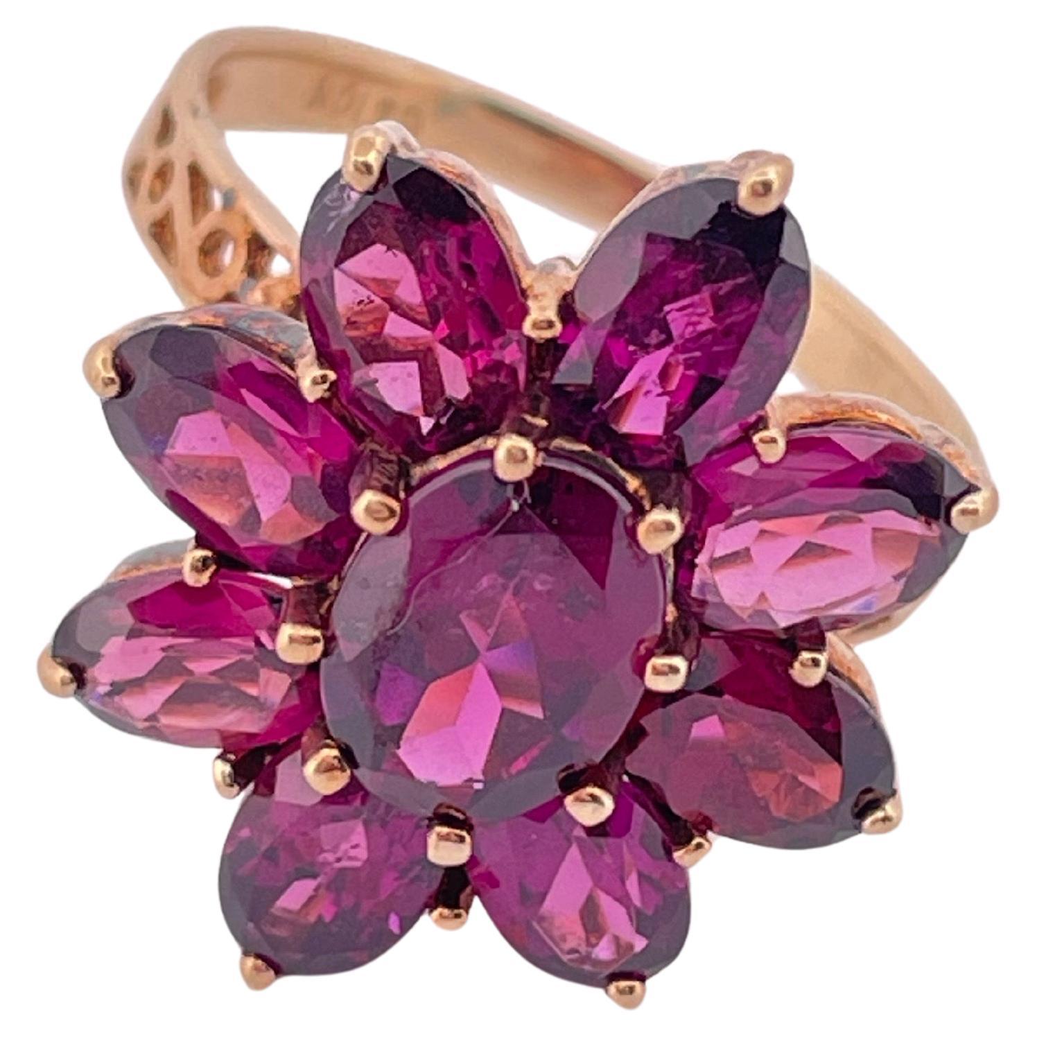 This striking floral ring is crafted in radiant 10k yellow gold and showcases a vivid display of deep pink to purplish-pink morganite gemstones. Designed in a bold, dimensional flower motif, the ring features a central oval-cut morganite surrounded
