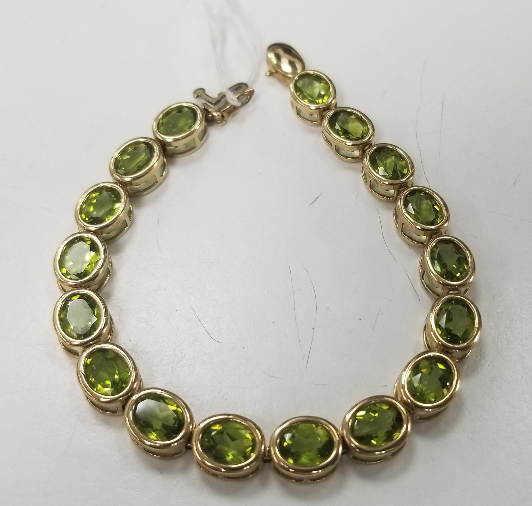 10k yellow gold peridot bezel bracelet, containing 17 oval cut peridot of gem quality weighing 17.00cts. measuring 7 inches with clasp and safety. 
