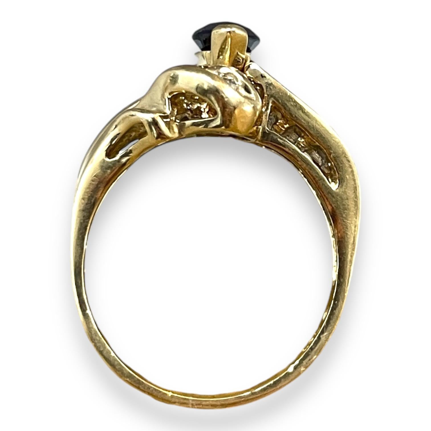 A sophisticated statement piece crafted in 10k yellow gold and weighing 5.9 grams, this ring features a mesmerizing marquise-cut sapphire at its center. The bold design is adorned with shimmering diamonds, gracefully set along the swirling gold