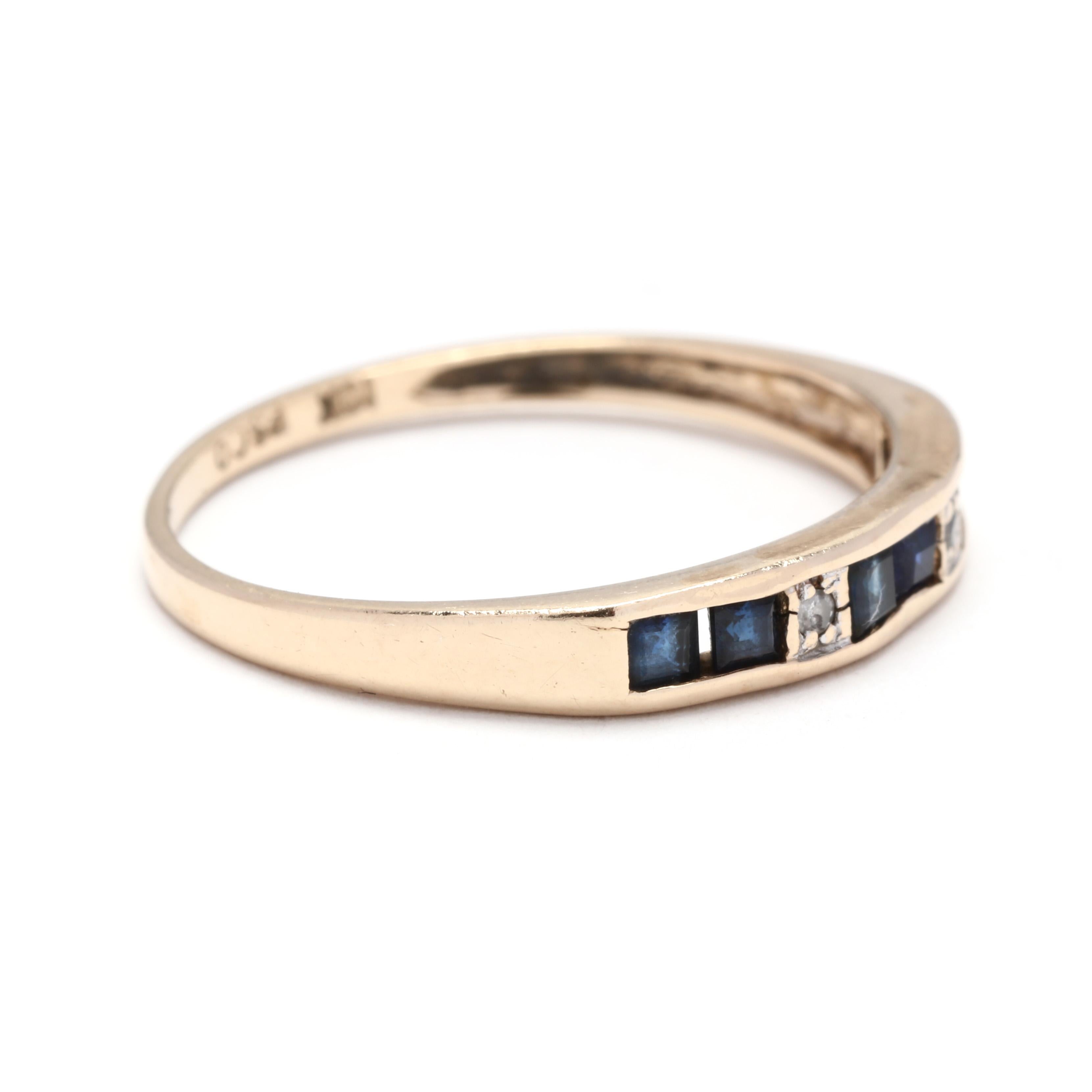 A 10 karat yellow gold, sapphire and diamond stackable band ring. A thin band with six channel set square cut sapphires weighing approximately .36 total carats, with two full cut round diamonds in between and a thin tapered band.

Stones:
-