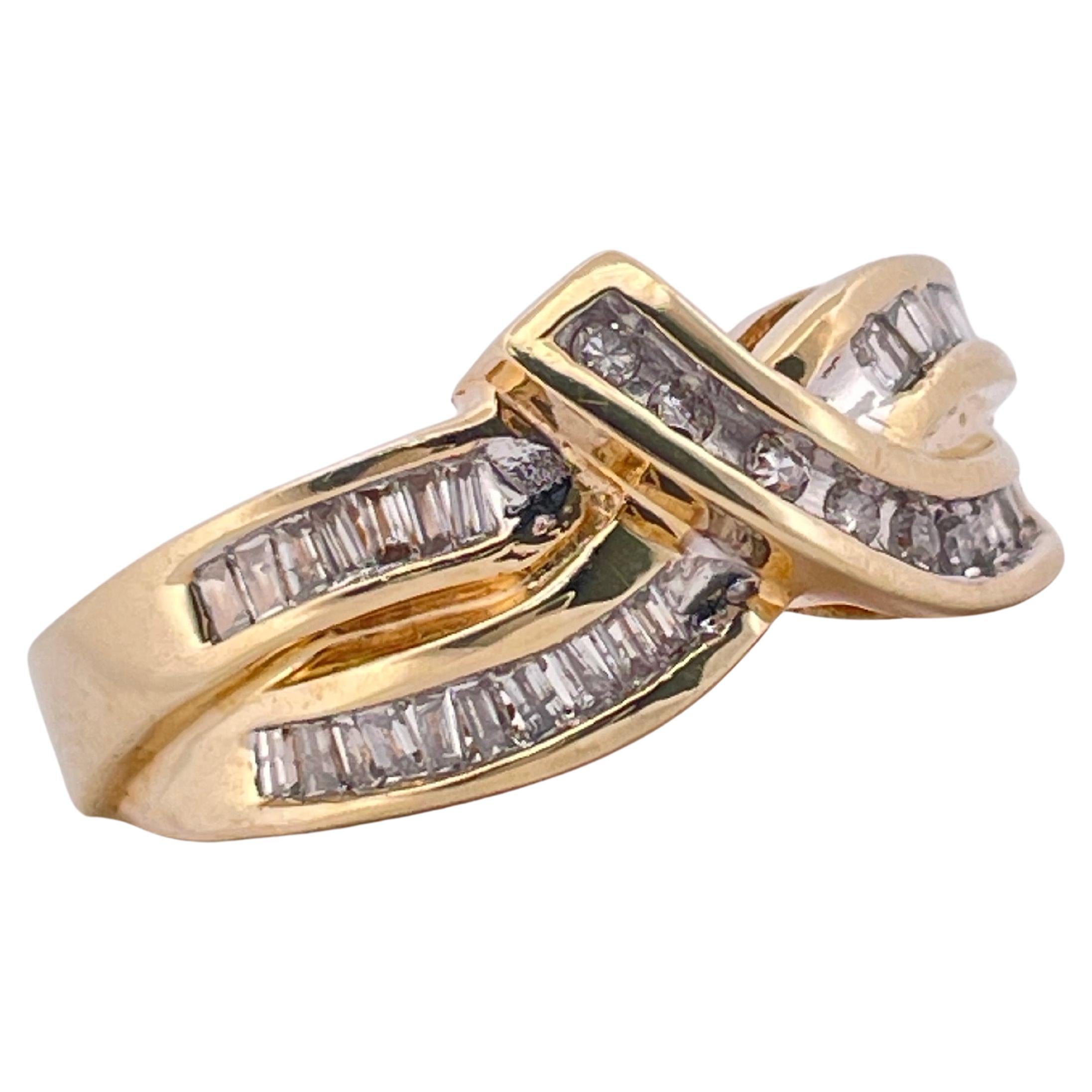 Questo elegante anello in oro giallo 10k sfoggia un sofisticato design incrociato, che emana un fascino senza tempo e una raffinata maestria. L'anello presenta scintillanti diamanti taglio baguette e tondi brillanti meticolosamente incastonati a