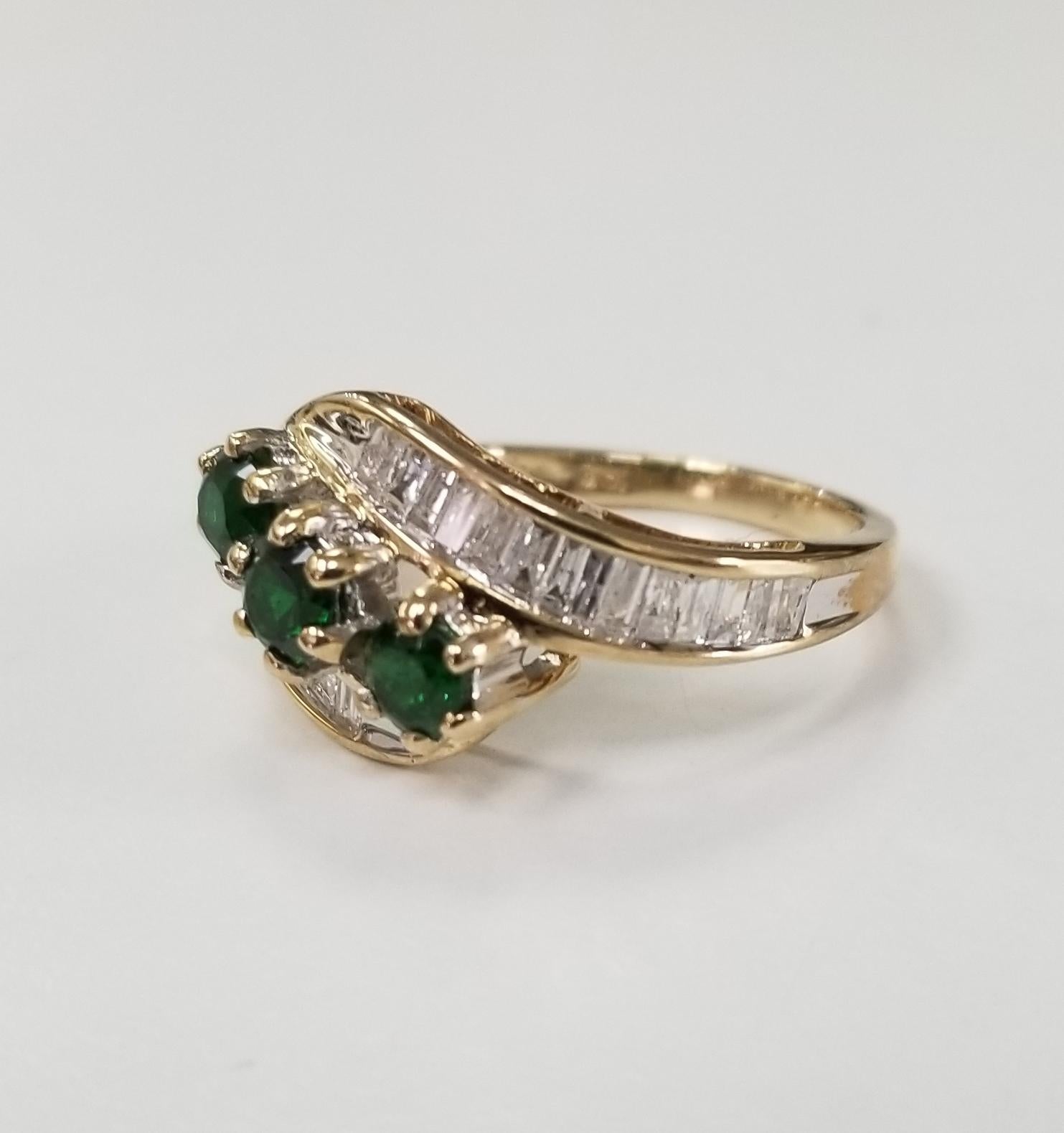 10k yellow gold tsavorite and diamond ring, containing 3 round tsavorite weighing 1.00cts. and 24 baguette cut diamonds weighing .70pts.  This ring is a size 7 but we will size to fit for free.

Tsavorite is a trade name for the emerald-green