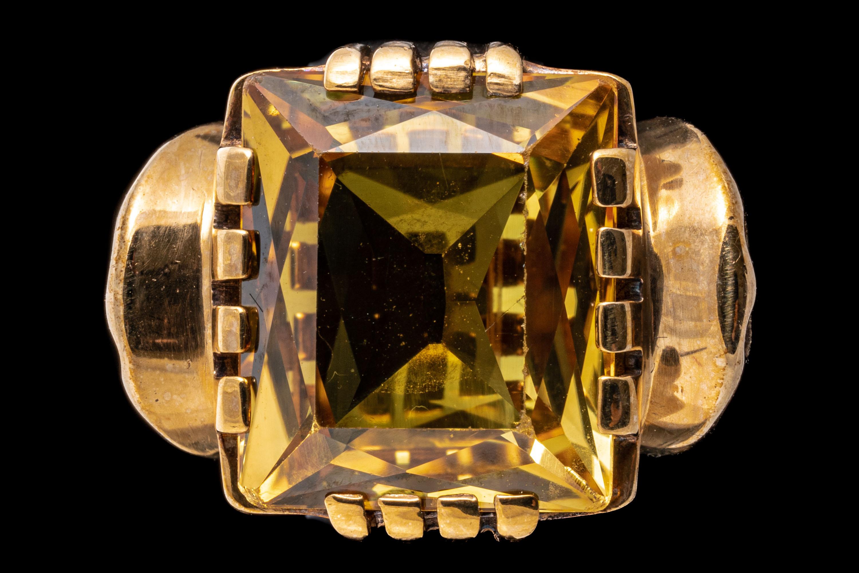 10k yellow gold ring. This handsome vintage ring is a 1950's style, with a square faceted, medium yellow color synthetic sapphire center, set in a notched style mounting with pierced fan motif shoulders.
Marks: None, tests 10k
Dimensions: 3/4