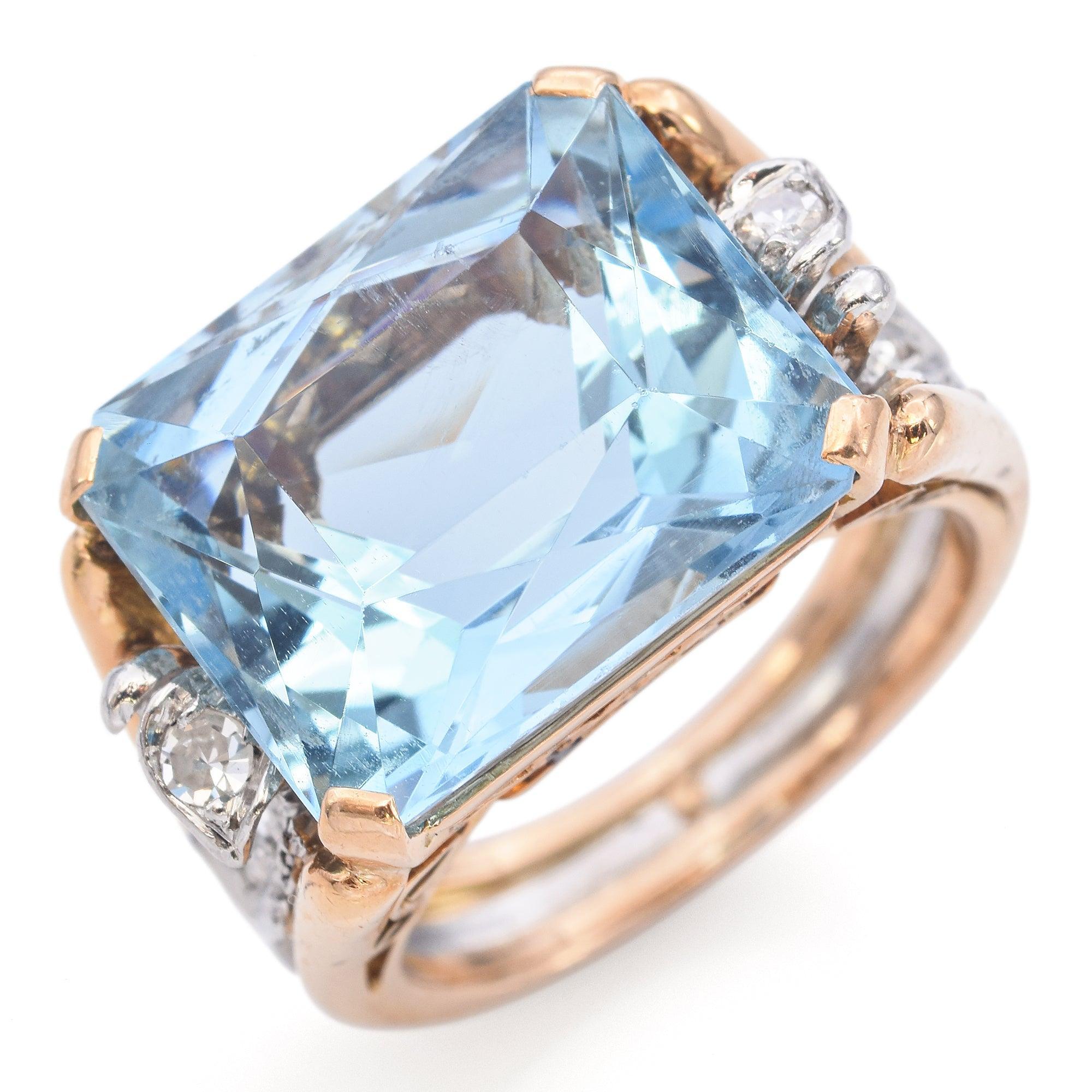 Un anello audace e luminoso che mostra un'acquamarina dal taglio radiante in una montatura in oro giallo 10K riccamente scolpita. Il design a gambo diviso presenta delicati accenti in filigrana d'oro bianco ornati da diamanti scintillanti, che
