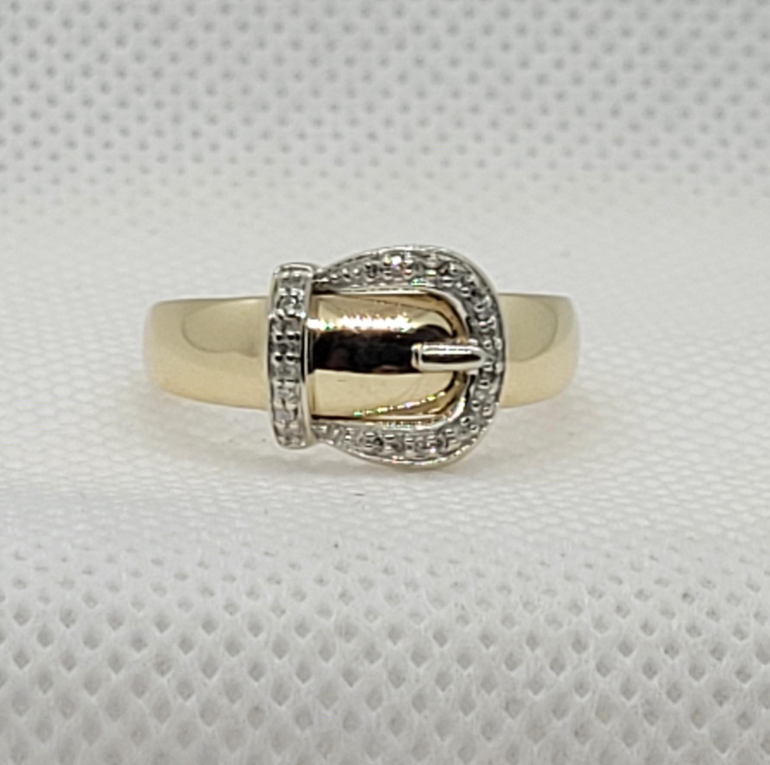 Stylish ladies 10kt two-tone gold ring with a belt buckle design accented with twenty-five single cut diamonds that are approximately .25cttw. The diamonds are prong set in white gold, H in color, and I in clarity. The ring is size 8, 3.2 grams, and