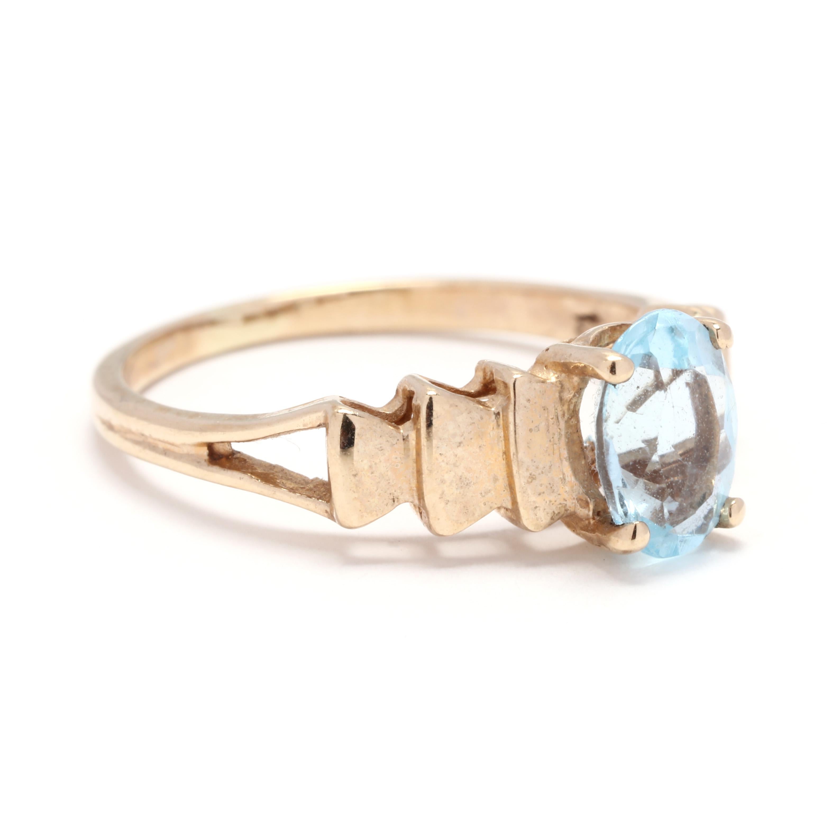 A 10 karat yellow gold blue topaz step ring. This ring features a prong set, oval cut blue topaz stone weighing approximately 1 carat set on a polished step mounting with a split shank.

Stones:
- blue topaz, 1 stone
- oval cut
- 7.22 x 5.22 mm
-