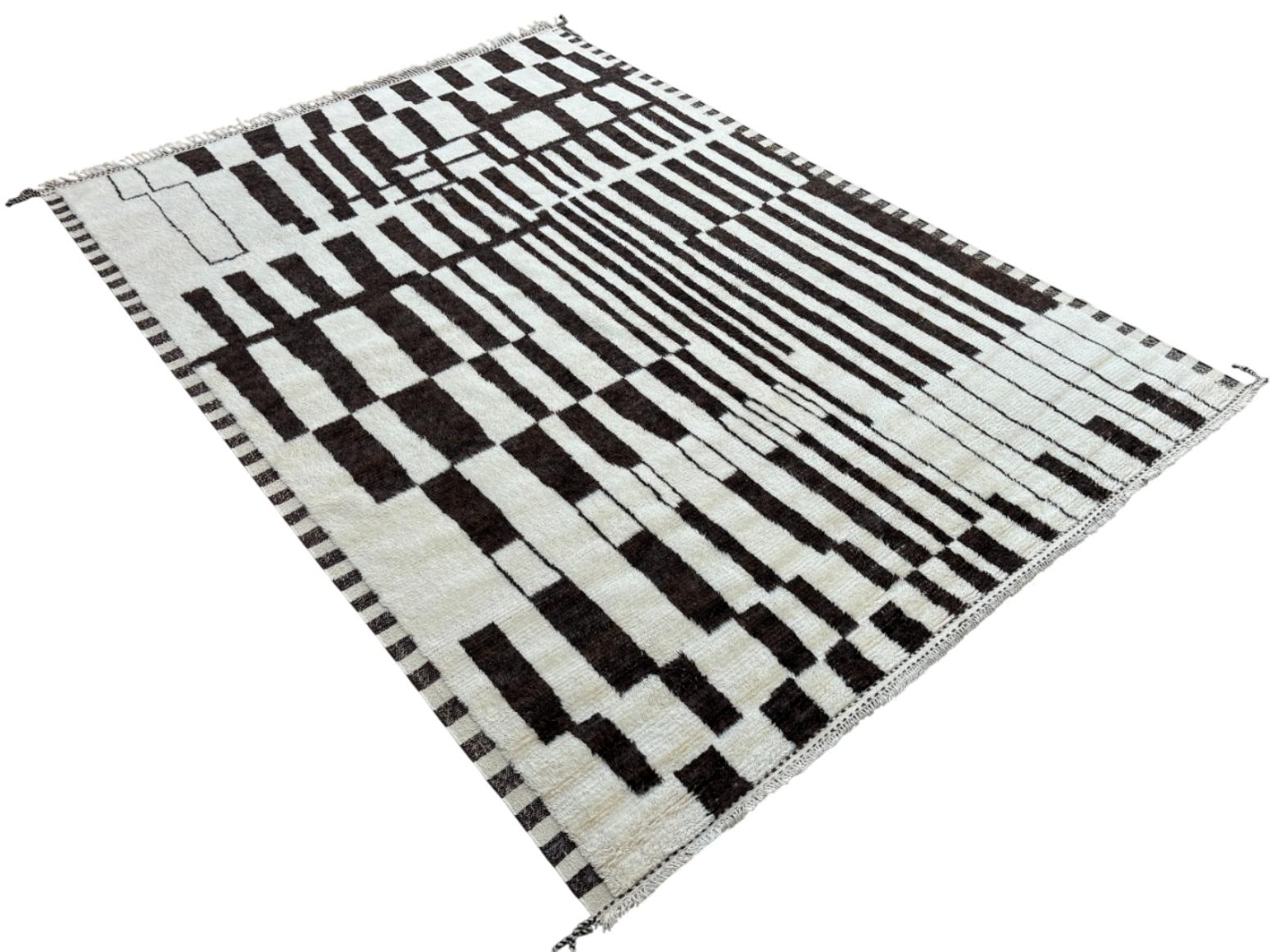 Eleva tu espacio vital con el exquisito encanto de esta nueva y moderna alfombra de diseño bereber marroquí Beni Ourain anudada a mano, elaborada con precisión y cuidado a partir de 100% lana. Combinando el encanto del estilo marroquí con la
