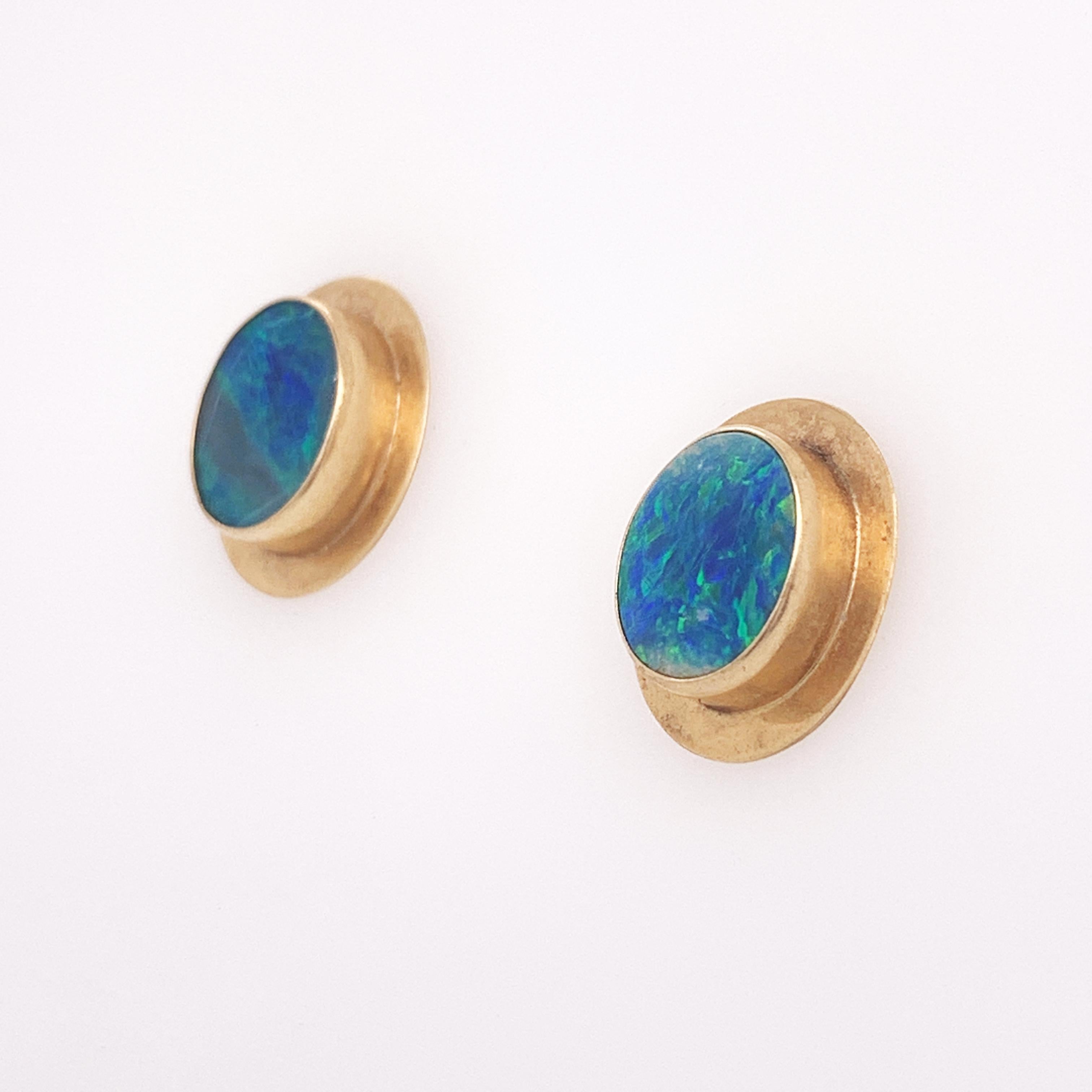 These medium sized opal stud earrings look as if they walked directly out of the 80's. The stunning and complimentary look of natural blue opals set in yellow gold is such a fun vintage style. Each earring centers around a small flat oval natural