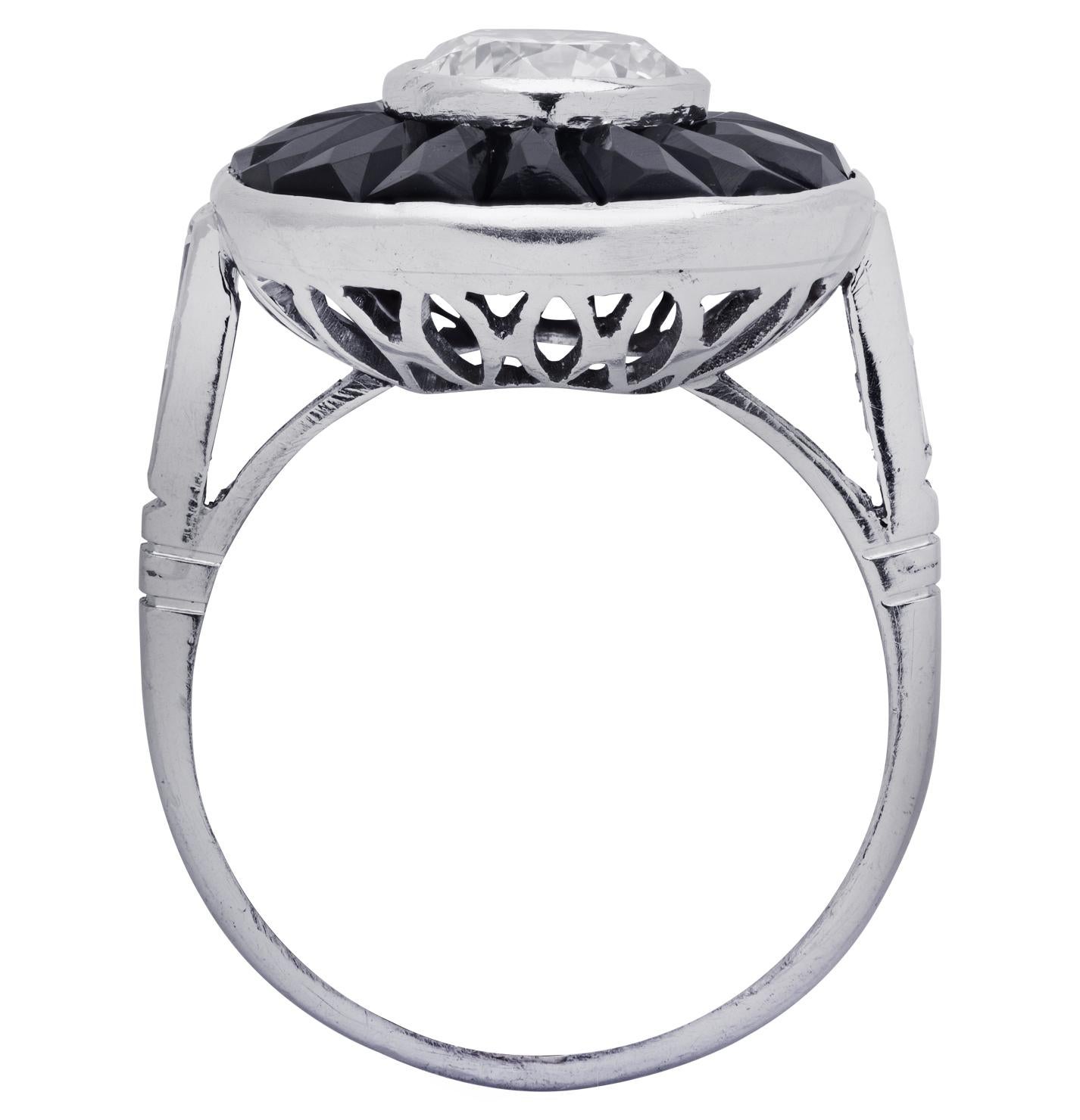 Stunning Art Deco style ring crafted in platinum showcasing a round brilliant cut diamond weighing approximately 1.1 carats G color, SI clarity and 4 baguette cut diamonds weighing approximately .25 carats total, G color, VS clarity. The diamond