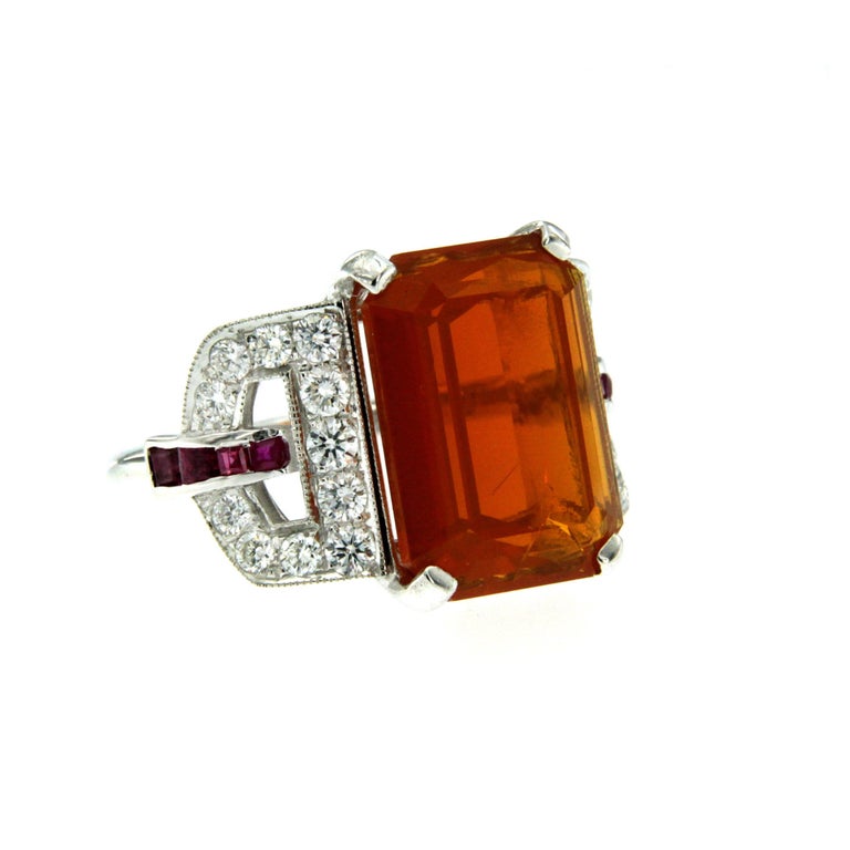 Stunning Art Deco ring set in the center with a beautiful fire opal weighing 11.67 carats, and surrounded by approx. 0.40 carat of custom cut Rubies and 0.90 ct of round brilliant cut diamonds. Remarkable gallerias work. Circa 1940

CONDITION: