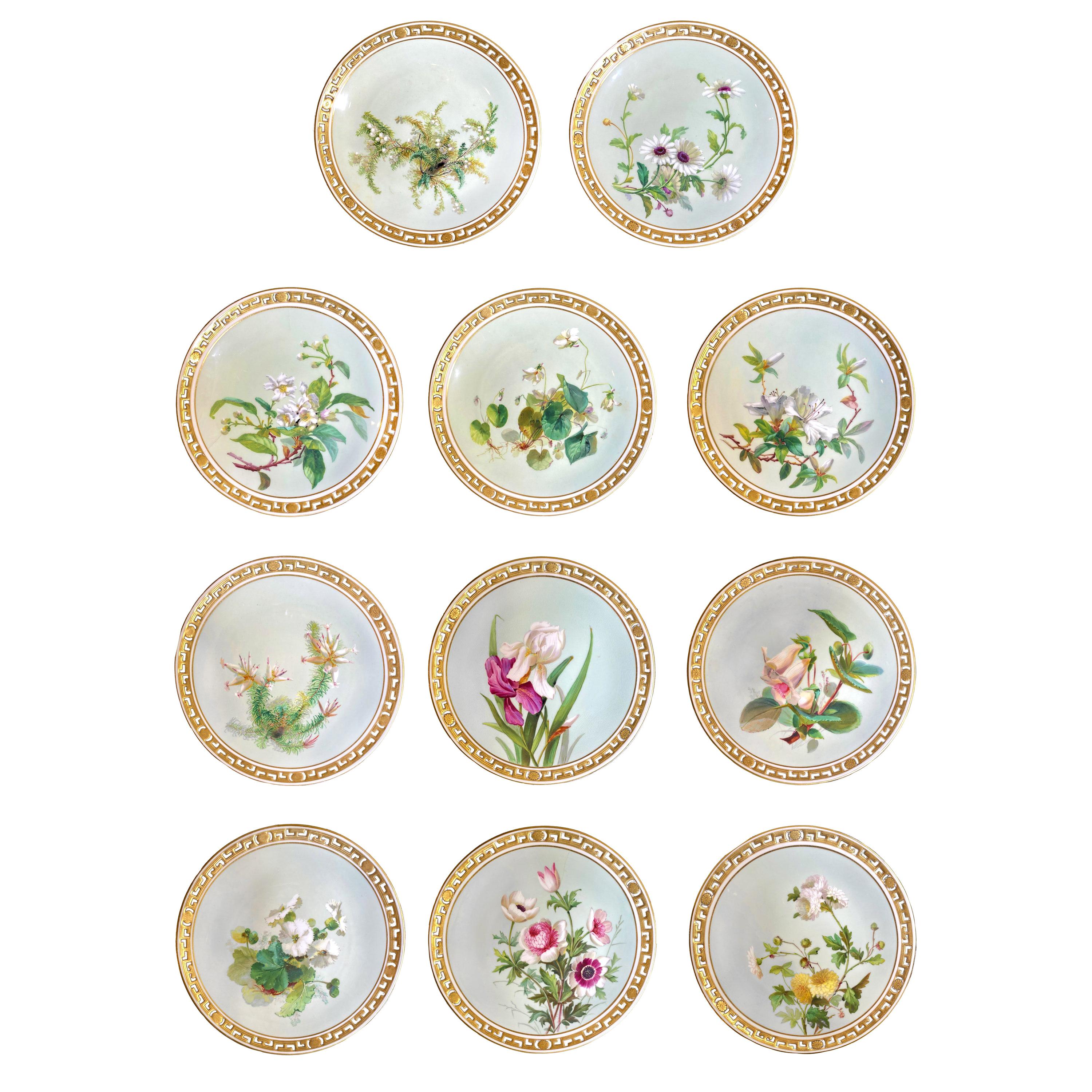 Set of 11 dinner plates in Minton Porcelain. Each plate is decorated with and hand painted flower on a green-blue background framed by a gold filet. The edge of the plate is openwork with a Greek style pattern alternated with some small flowers and