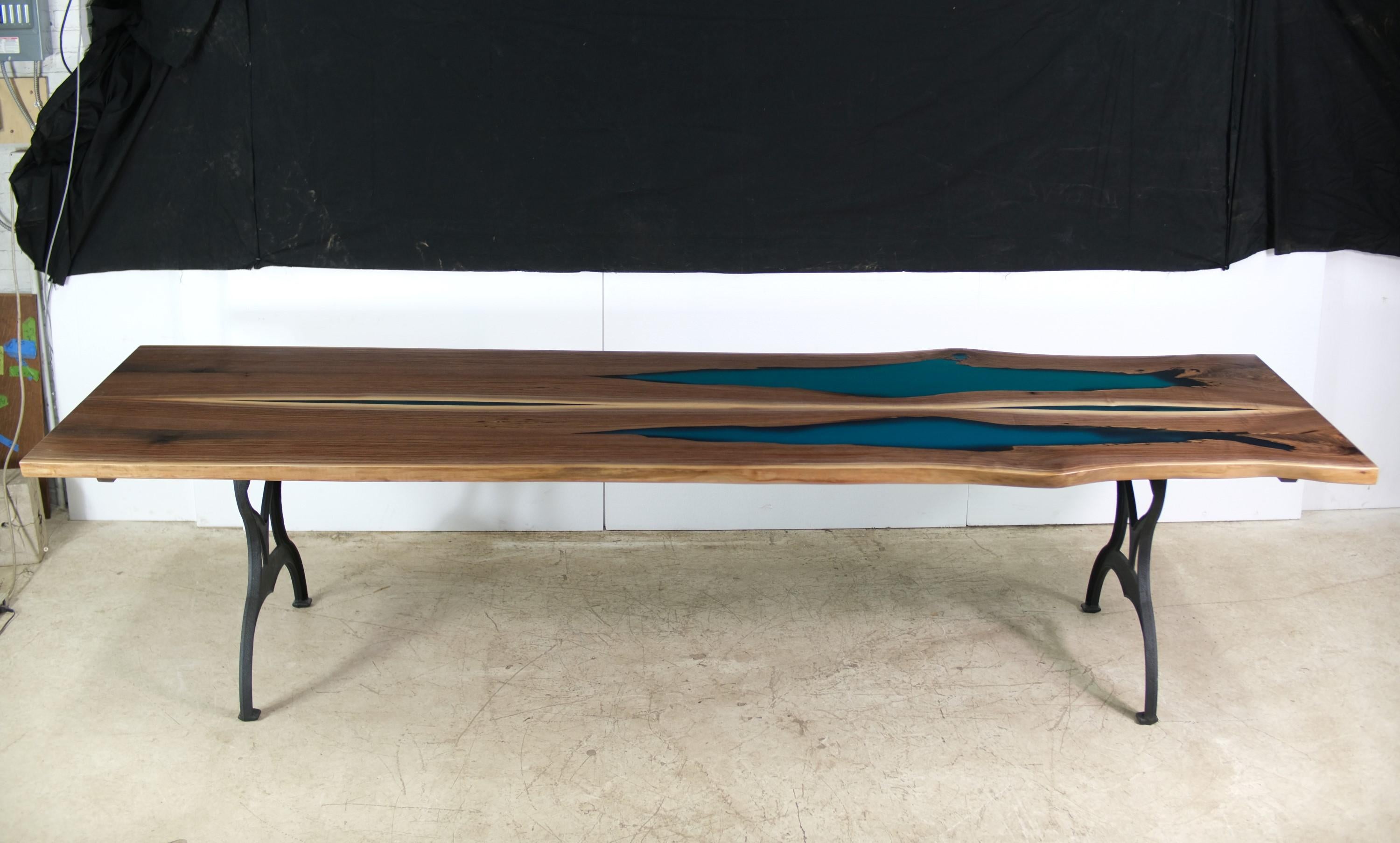 Cette table présente un plateau en noyer papillon à quatre dalles avec une coulée de résine bleue, associé à des pieds en fonte de Brooklyn New York. Cette table est prête à être expédiée. Veuillez noter que cet article se trouve dans l'un de nos