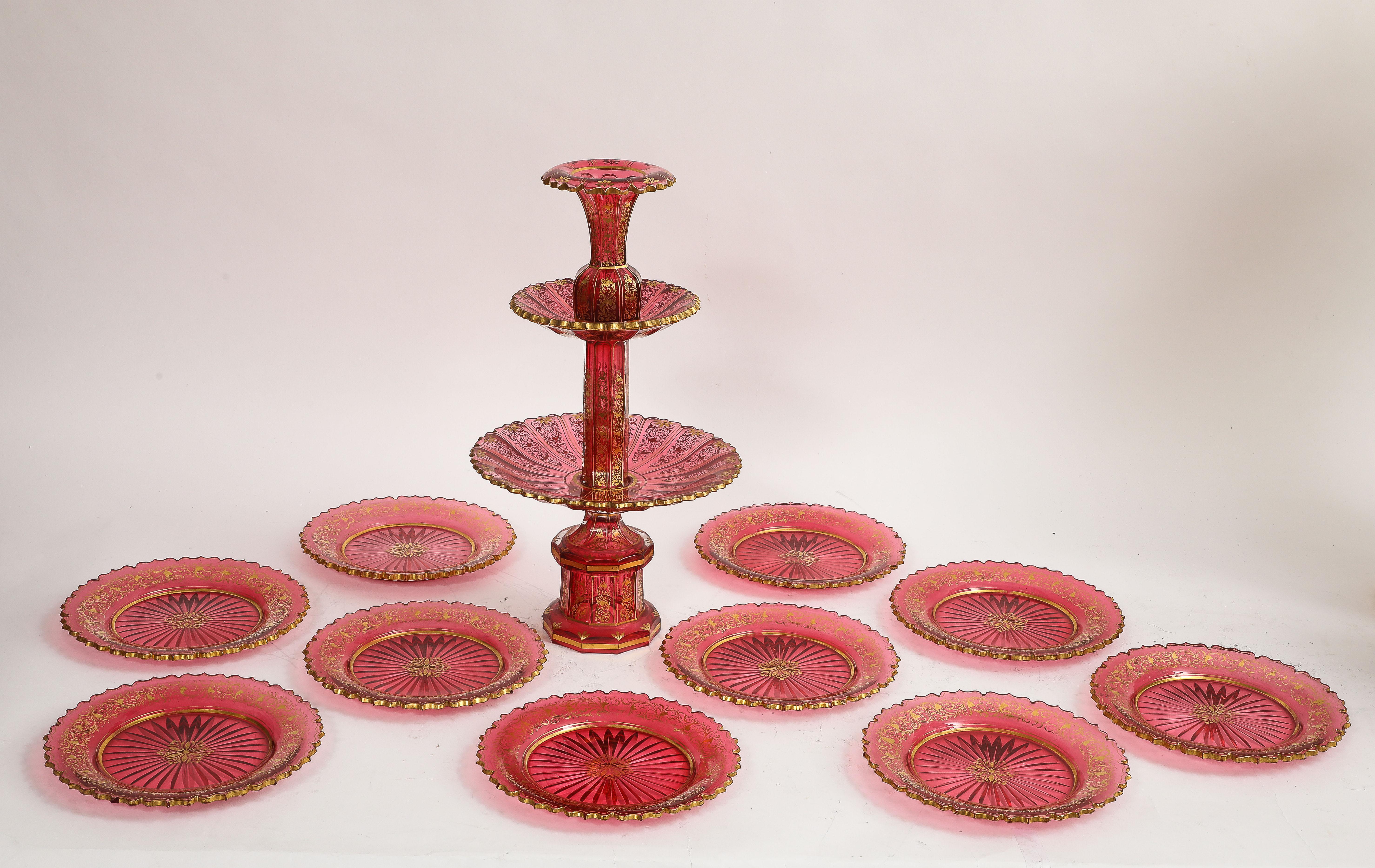 A Large and Quite Gorgeous Eleven-Piece Baccarat Cranberry-Red Crystal Two-Tier Cake Stand with Matching Plates.  The set comprises a central two-tier cake stand accompanied by ten matching plates, all executed in cranberry-red crystal. The cake