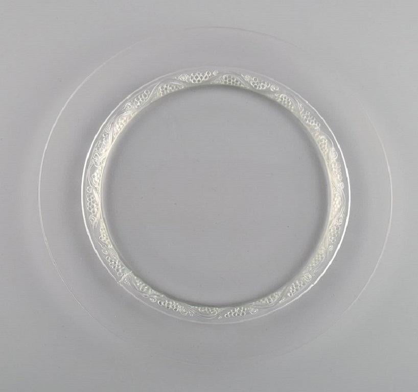 11 platos René Lalique Phalsbourg de vidrio artístico transparente con vides y uvas en relieve. 
Mediados del siglo XX.
Diámetro: 22,5 cm.
En excelente estado.