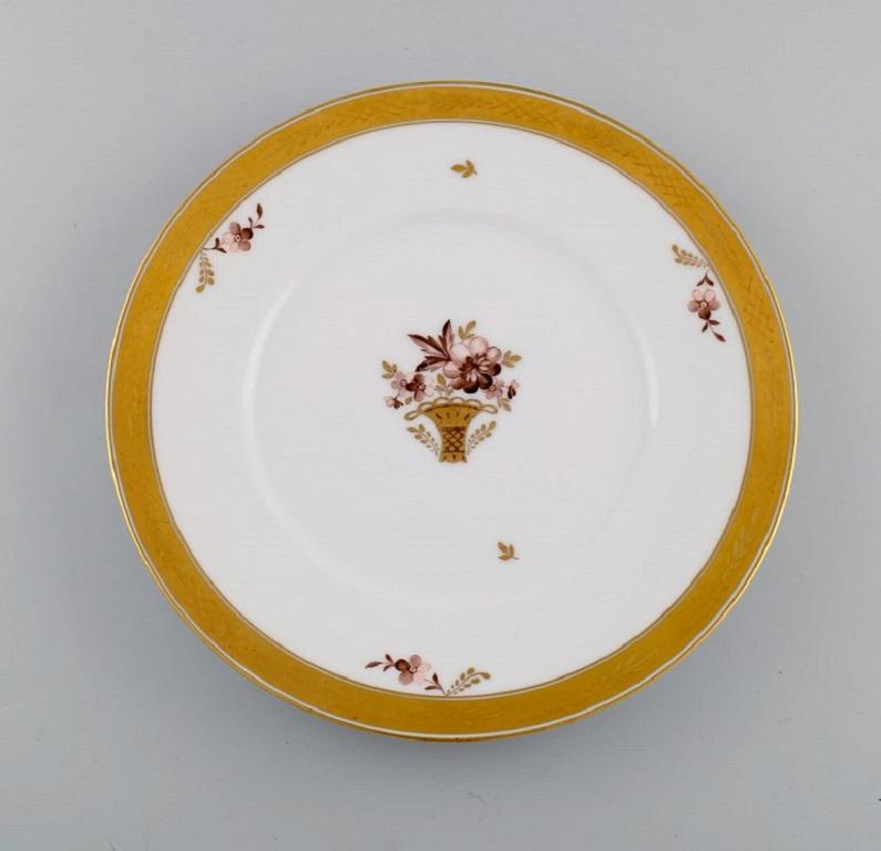 11 Royal Copenhagen golden basket porcelain dinner plates with flowers and gold decoration. 
Model number 595/10519. 
Early 20th century.
Measure: Diameter: 25.5 cm.
In excellent condition.
Stamped.
1st factory quality.