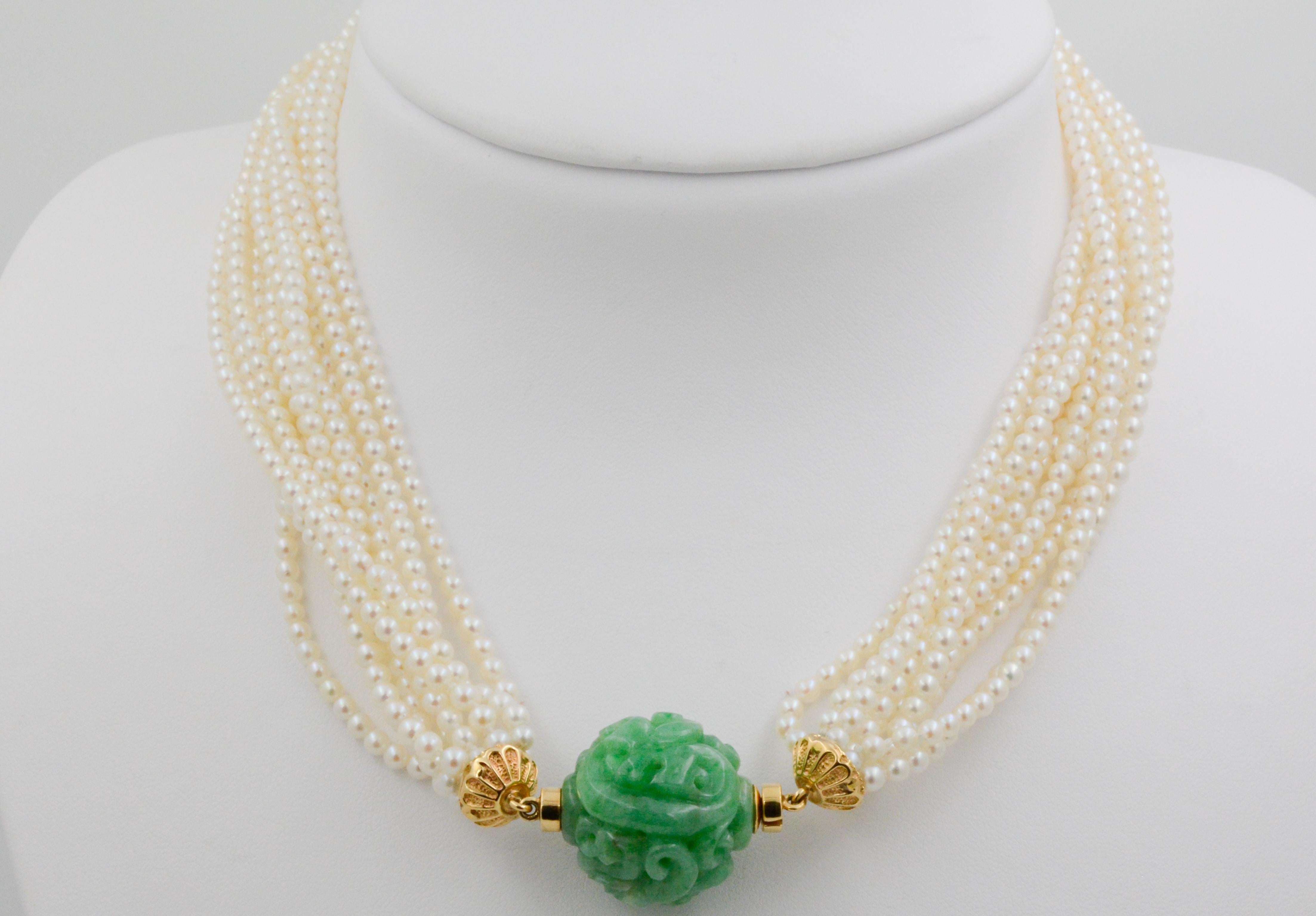 This hand-strung eleven strand necklace's 2.74mm Akoya pearls are accompanied by a 21.84mm carved green jade bead. The jadeite tongue and groove clasp is secured with 18K yellow gold roundels. This stunning necklace measures 16