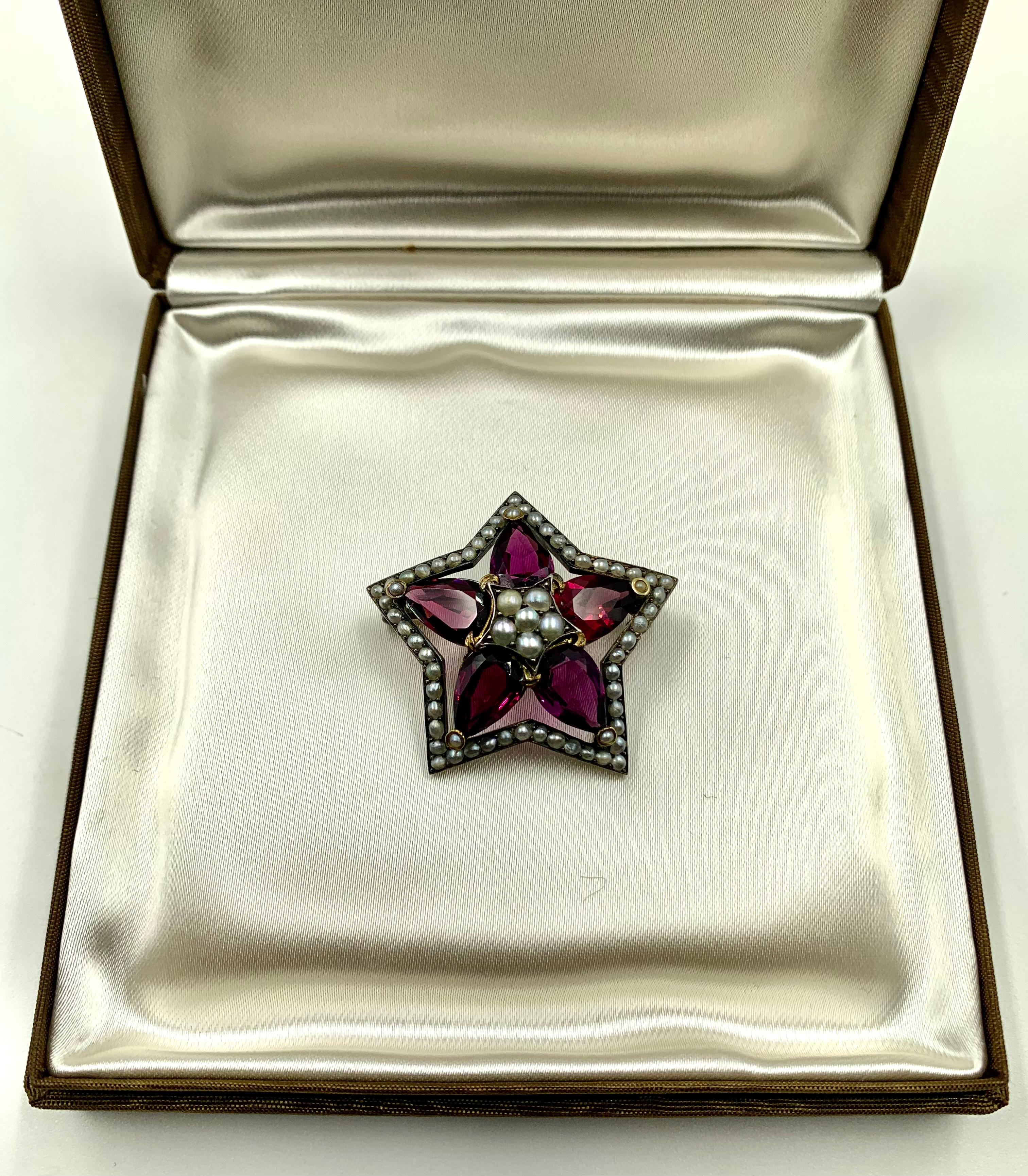 Striking star brooch featuring five rich burgundy colored pear shaped Rhodolite garnets with total carat weight of approximately 11 Carats. 
Apparently unmarked, the center setting tests for 18K gold with the surrounding oxidized setting testing for