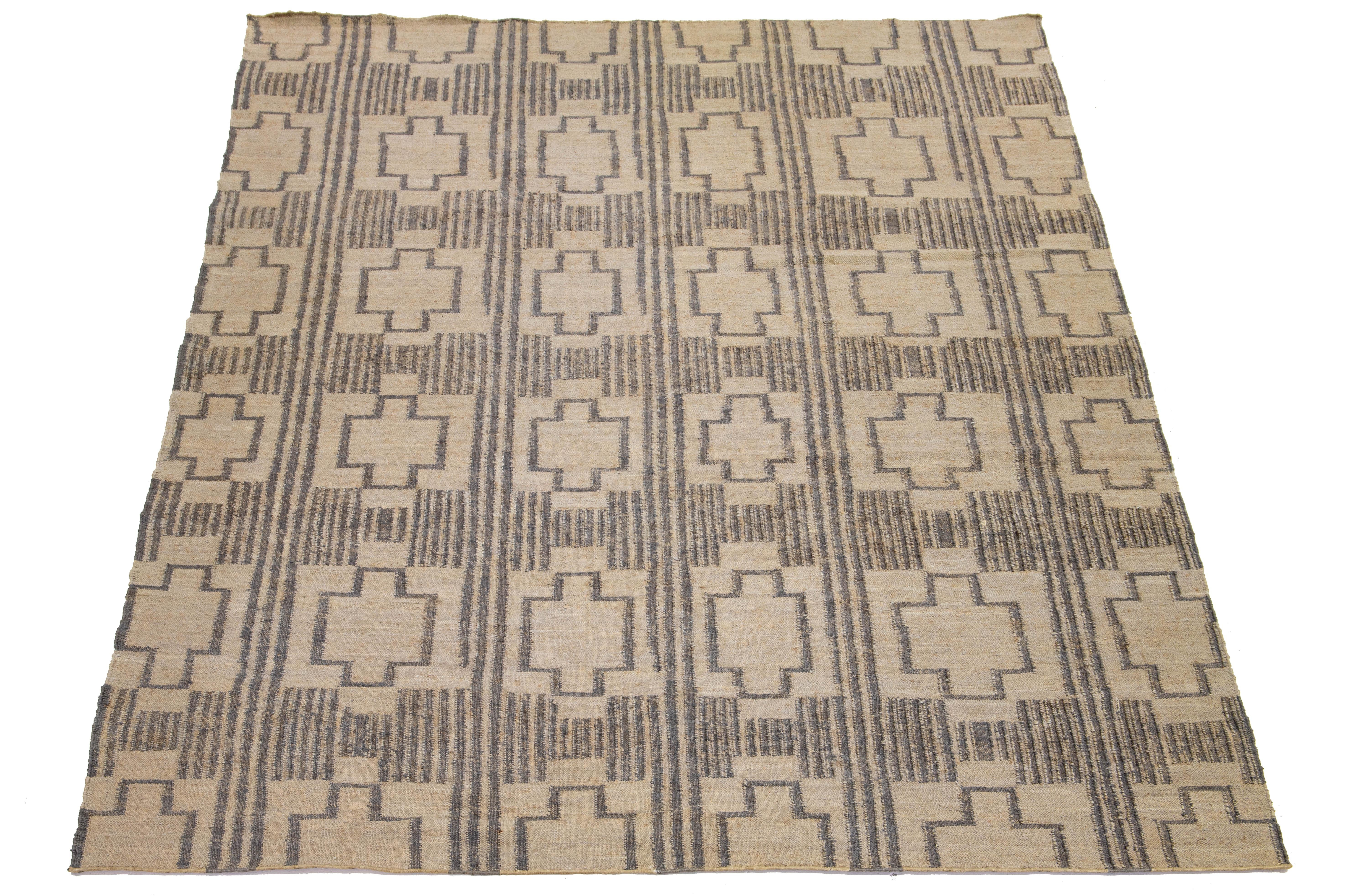 This flatweave natural jute rug showcases a contemporary Dhurrie design, featuring a tan-beige base color and stylish gray geometric accents.

 This rug measures 10'7