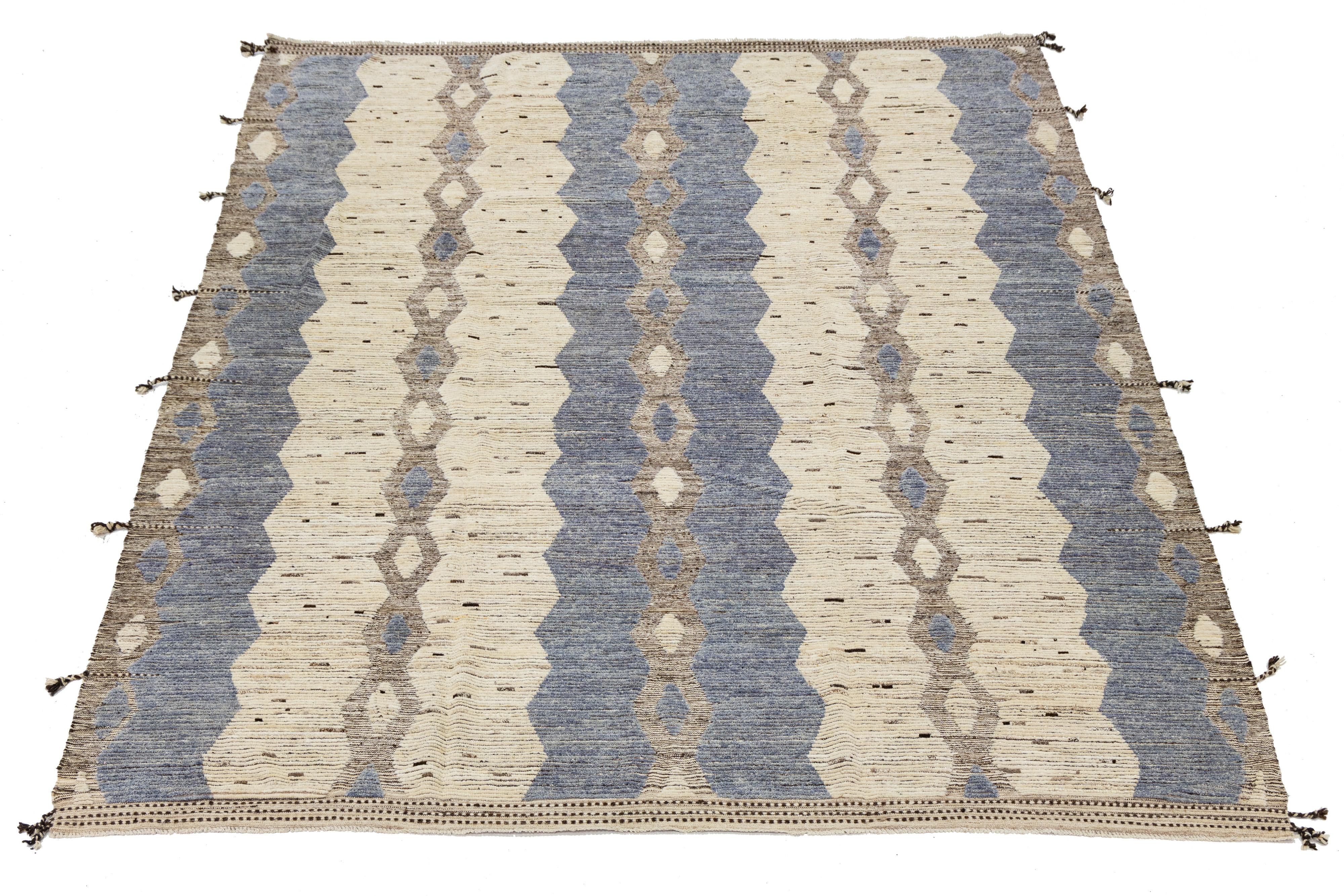 Dieser wunderschön gefertigte Wollteppich mit seinem eleganten, beigefarbenen Hintergrund ist ein Beispiel für modernes marokkanisches Design. Die moderne Komposition zeichnet sich durch eine auffällige Mischung aus Blau und Braun aus und sorgt für