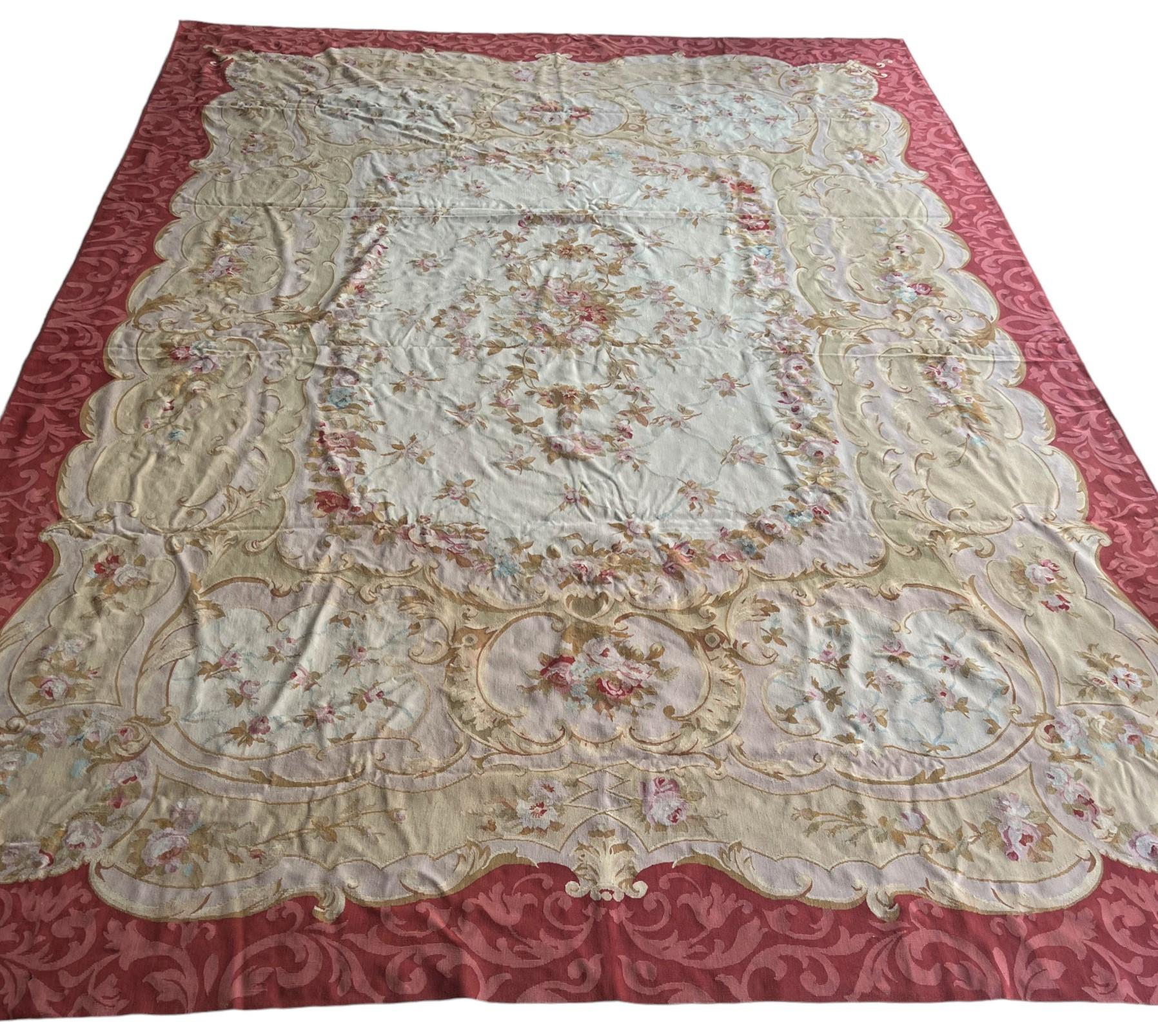 Un tappeto Aubusson dal design classico con disegni di fiori, fogliame e volute circondati da un bordo rosa. I tappeti Aubusson sono privi di pelo e sono tessuti allo stesso modo degli arazzi.
Situata sulle rive del fiume Creuse in Francia, Aubusson