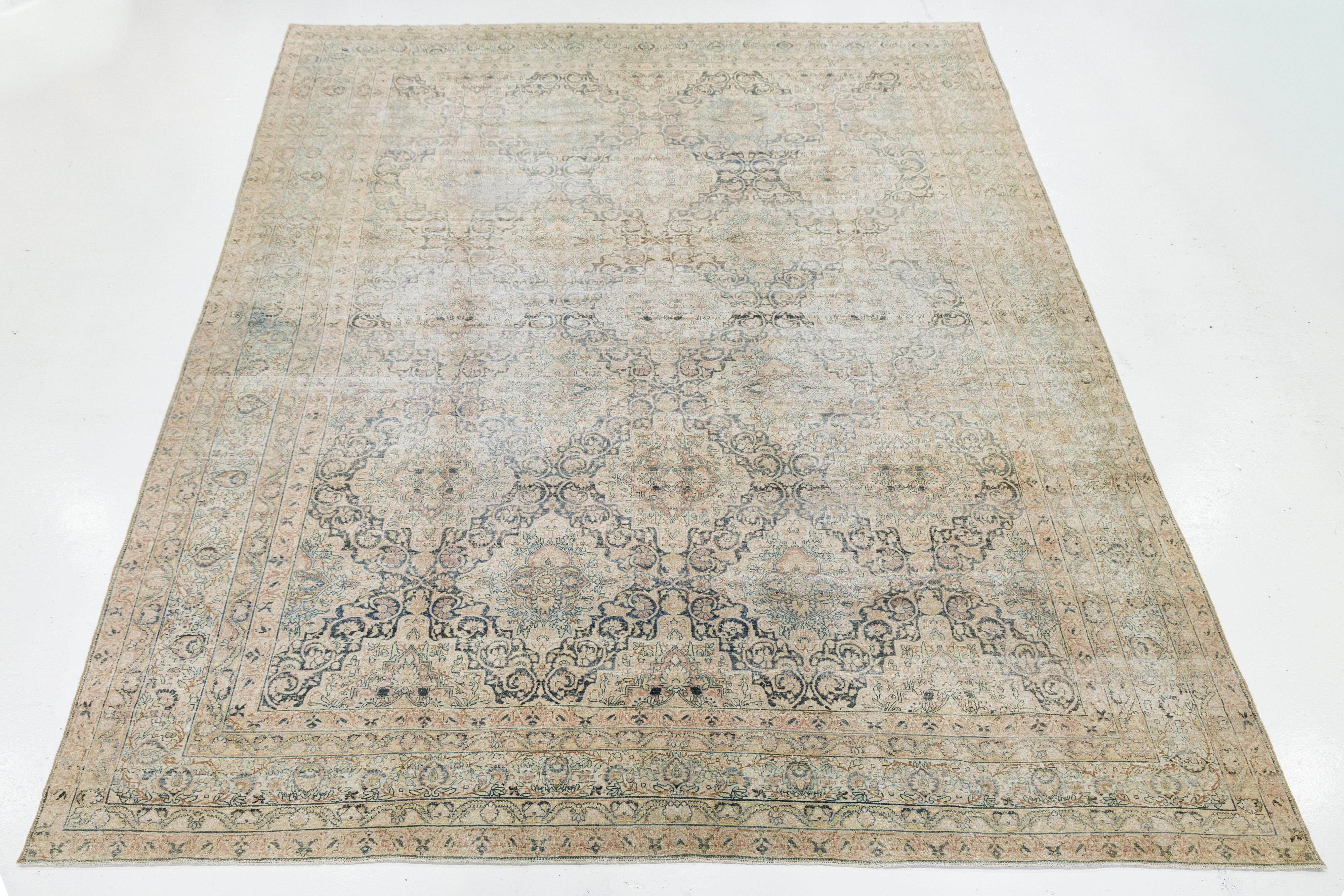 Dieser authentische antike Kerman-Teppich zeichnet sich durch ein raffiniertes Medaillonmuster mit komplizierten Blumenmotiven in gedämpften Beige-, Blau- und Grüntönen aus. Er ist aus feiner Wolle handgeknüpft und zeichnet sich durch klassische