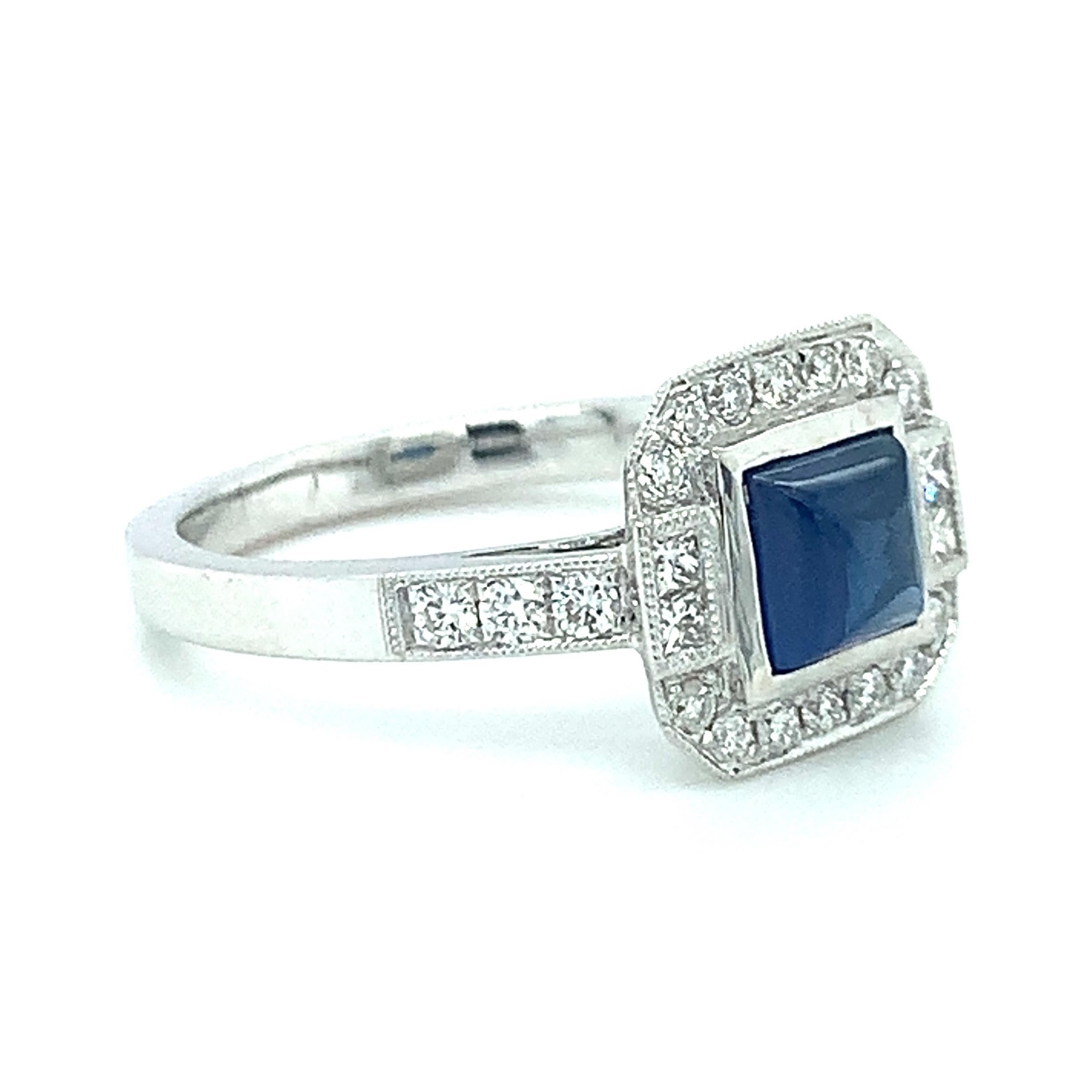 This pretty cocktail ring features an unusual center stone: a blue sapphire square cabochon! The sapphire has been bezel set in 18 white gold to highlight the gem's beautiful outline, with a row of scintillating diamonds pave set around it in a