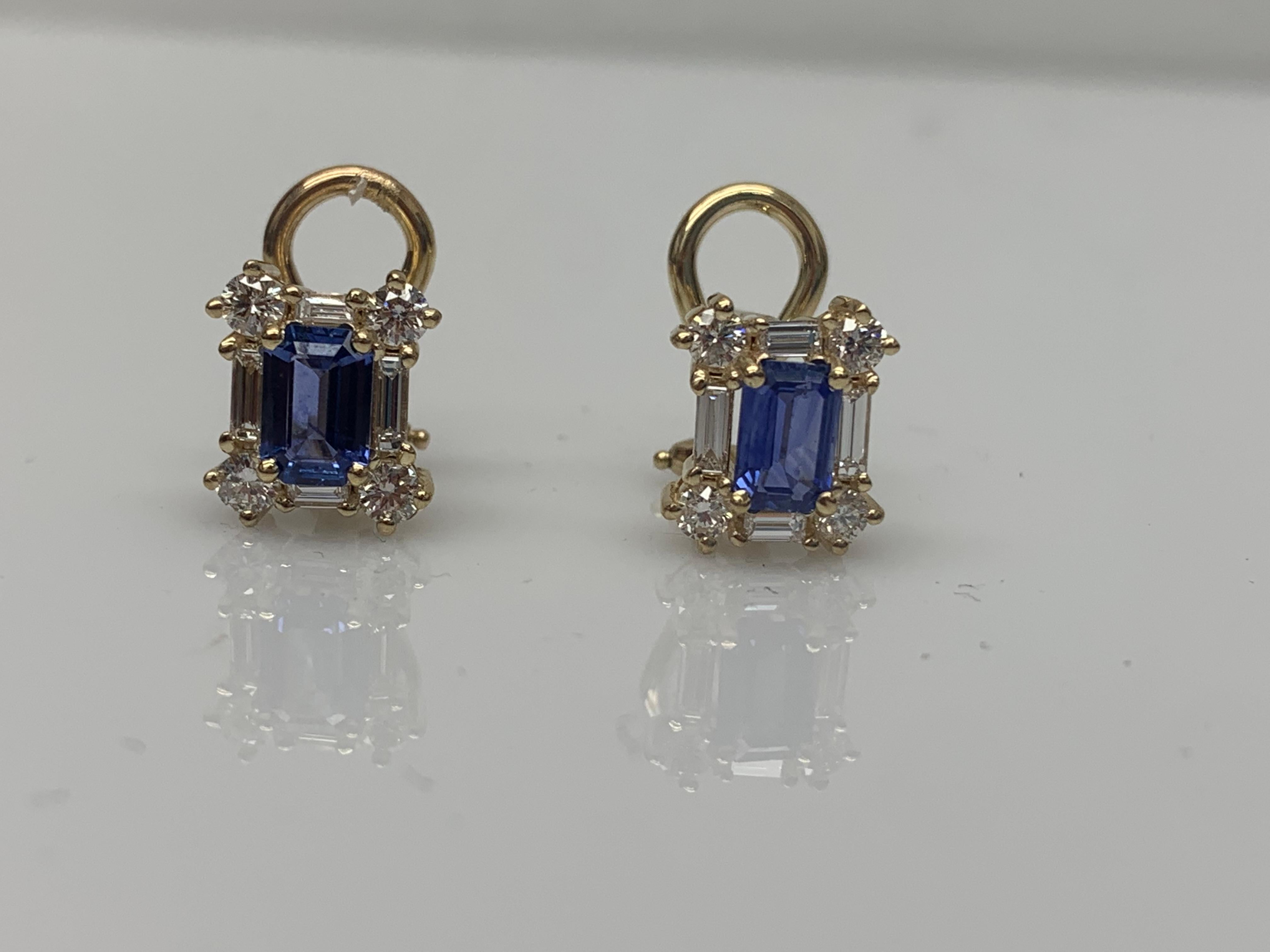 Boucles d'oreilles à la mode mettant en valeur deux saphirs bleus de 1,01 carat taillés en émeraude, luxuriants et vibrants. La pierre centrale est entourée d'une rangée de diamants taille brillant, 8 diamants ronds et 8 diamants baguettes, pesant