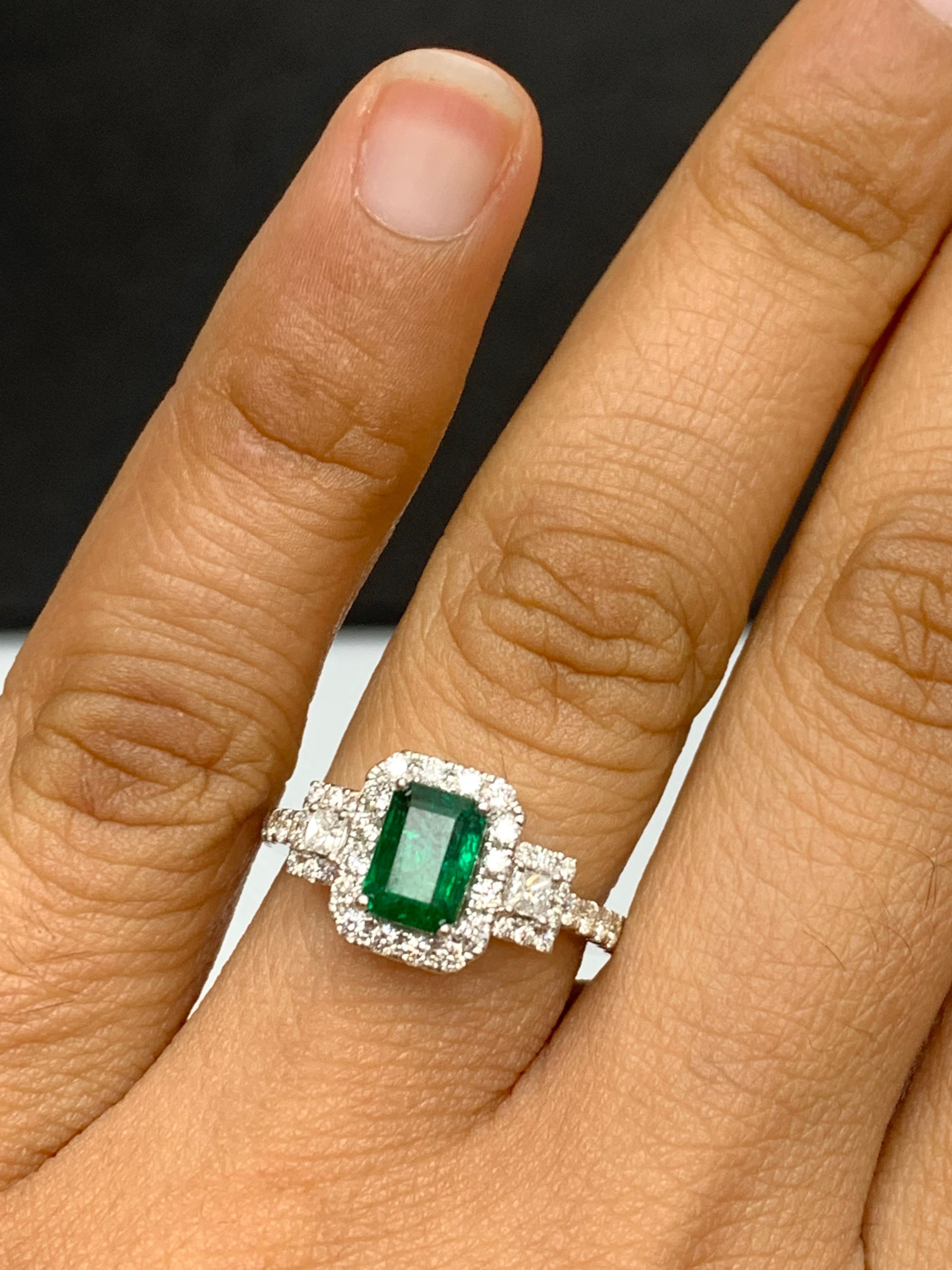 A stunning ring showcasing a rich lush green emerald cut Emerald weighing 1.10 carats surrounded by diamonds on both sides. 42 diamonds on each side weighing 0.57 carats in total. Made in 18K Rose Gold.