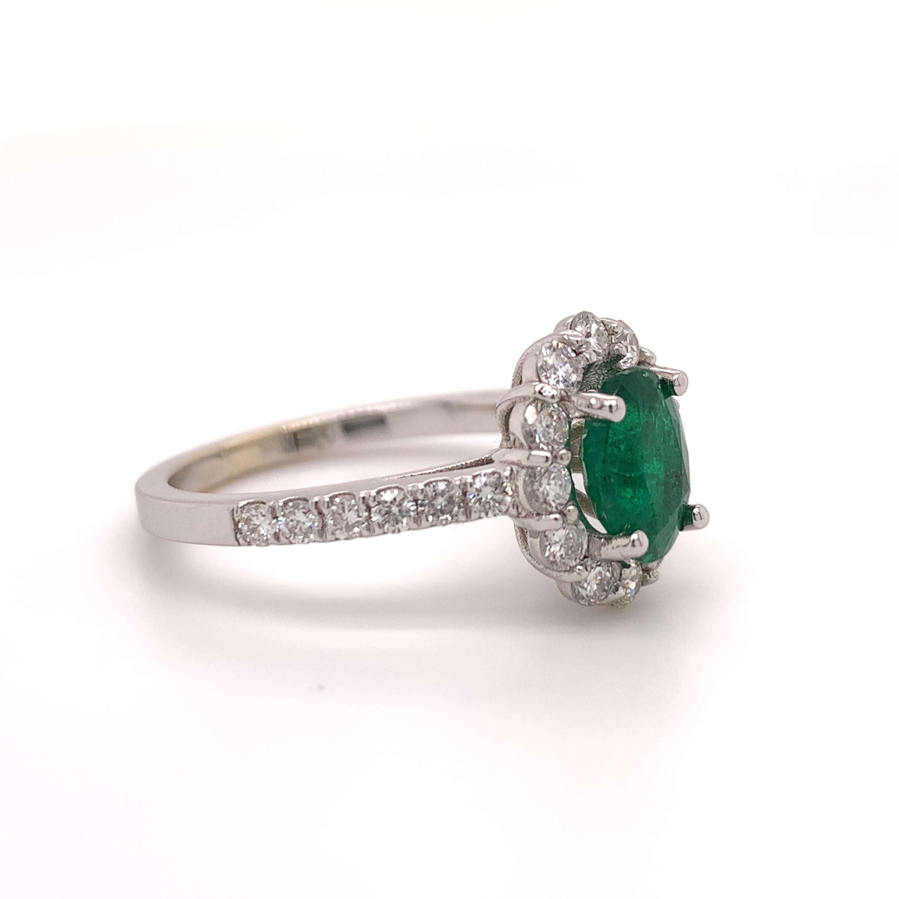Classic halo design emerald ring. High brilliance, rich green, oval faceted natural 1.10 carats emerald mounted in high profile open basket with four bead prong, accented with round brilliant cut diamonds. Handcrafted classic design set in high