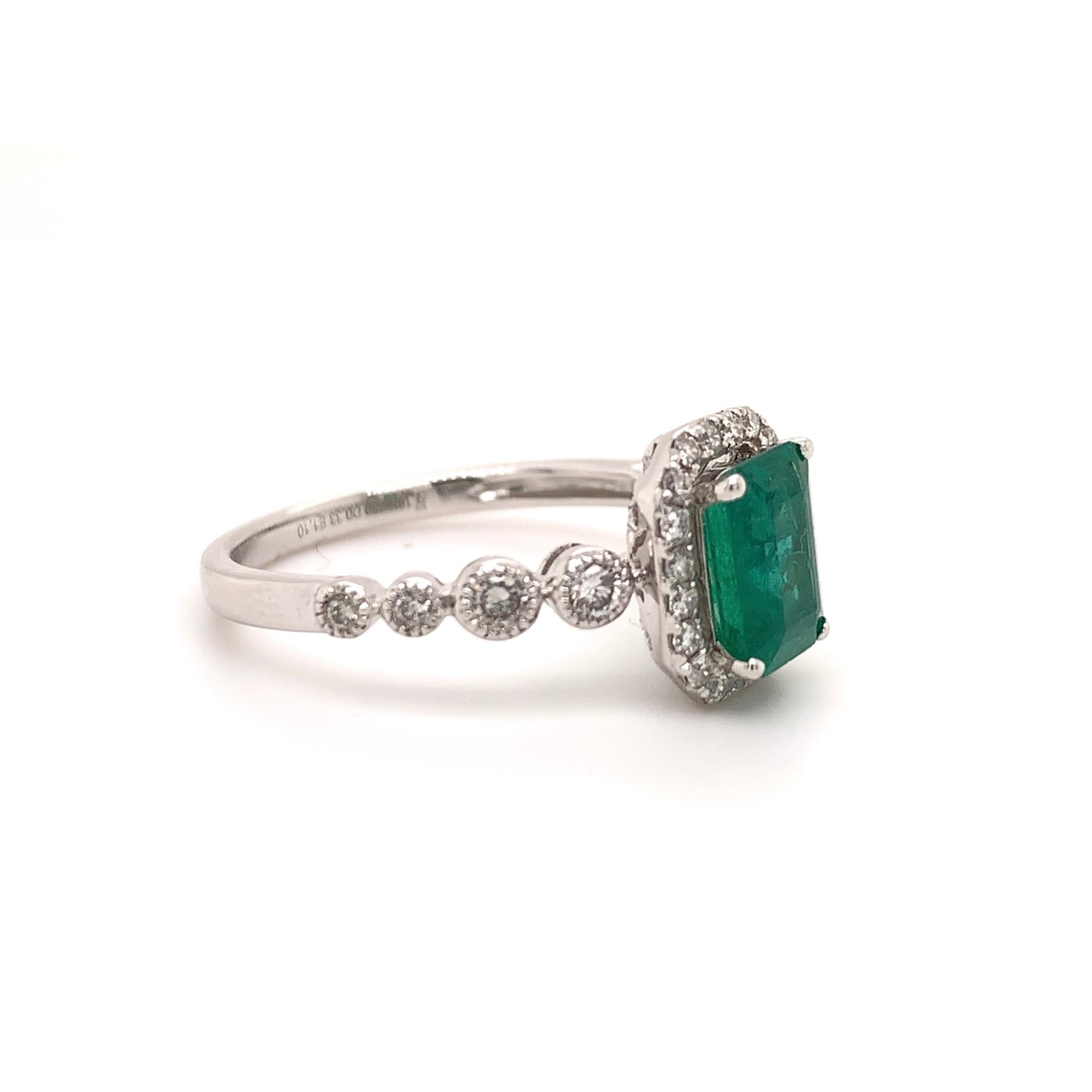 Lively bluish green natural emerald cut emerald & diamond ring. Mounted in high profile setting with four prongs, & open back basket. Accented with round brilliant cut diamond frame, & shank. 
Beautiful handcrafted design set in 18 karat white gold.