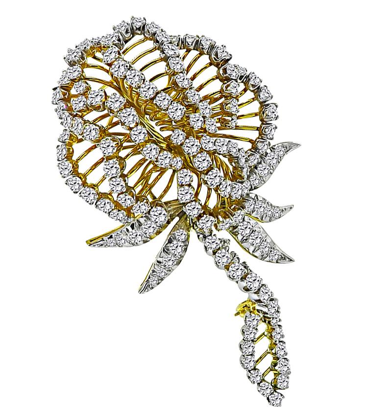 This is a stunning 18k yellow and white gold flower pin. The pin is set with sparkling round cut diamonds that weigh approximately 11.00ct. The color of the diamonds is F-G with VS clarity. The pin measures 79mm by 45.5mm and weighs 36 grams. The