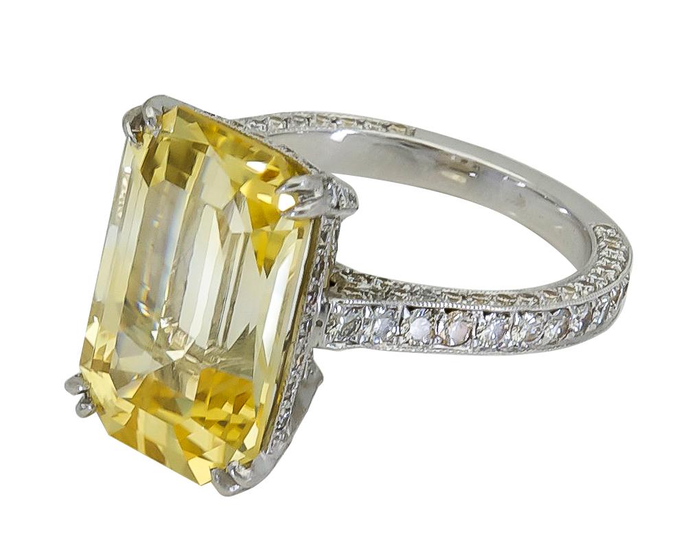 Ein prächtiger Verlobungsring mit einem langen gelben Saphir im Smaragdschliff, eingefasst in einen mit Diamanten besetzten Korb und Schaft. Hergestellt aus Platin.
Der gelbe Saphir wiegt 11,06 Karat. 
Größe 6 US (größengerecht)
Abmessungen: 0.62