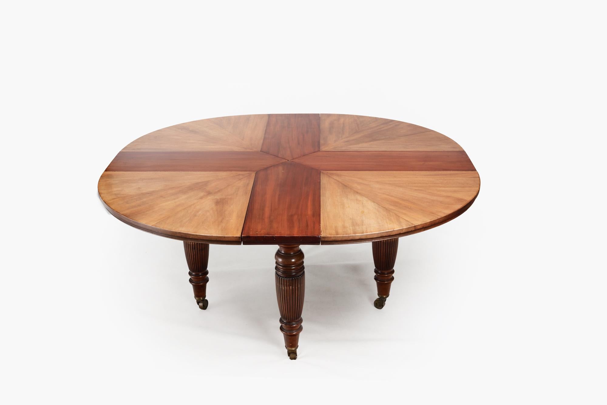 19th Century ‘Jupe’ style extendable dining table stamped and numbered Maple & Co of London. This circular mahogany dining table has a segmented top supported on four turned and reeded legs. The table has four removable leaves that can be added,