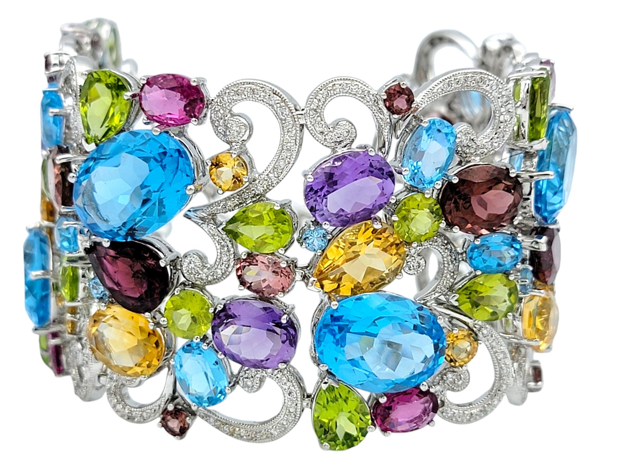 Schmücken Sie Ihr Handgelenk mit der fesselnden Schönheit dieses breiten Armbands aus 14 Karat Weißgold, einer atemberaubenden Verschmelzung von kompliziertem Design und leuchtenden Farben. Das Armband ist mit einem filigranen Wirbelmuster verziert,