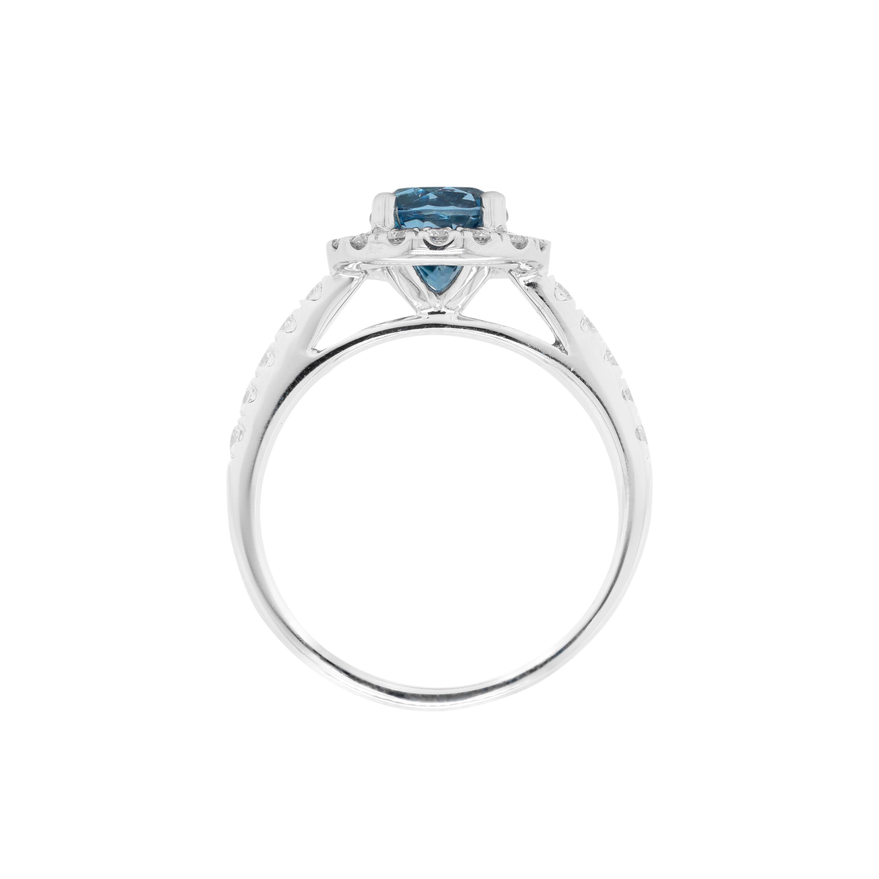 This stunning cluster engagement ring features a beautiful round aquamarine weighing 1.10ct, mounted in a four claw, open back setting. The vibrant stone is surrounded by a halo of 16 round brilliant cut diamonds sat atop a delicate mount with 5