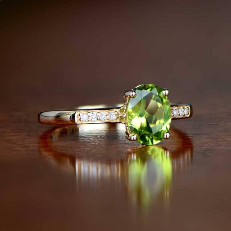 This exquisite August birthstone ring boasts a captivating oval-cut peridot center stone with a charming green hue. Adorned with diamonds along the shoulders, the ring emanates timeless beauty. The peridot, weighing approximately 1.10 carats,