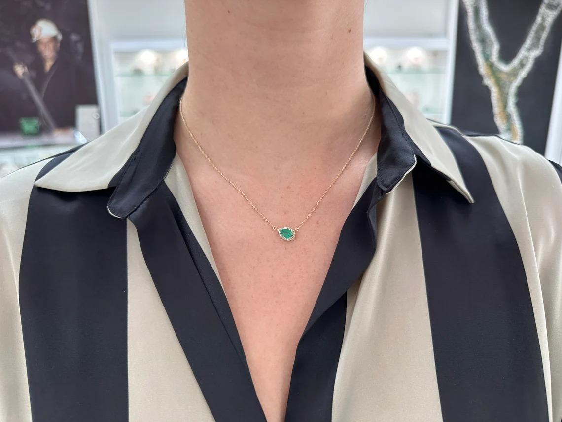 This natural pear cut emerald and diamond halo necklace is an exquisite piece of jewelry that is sure to turn heads. The center stone is a pear cut emerald with a medium dark green color, set in a three prong setting to showcase its natural beauty.