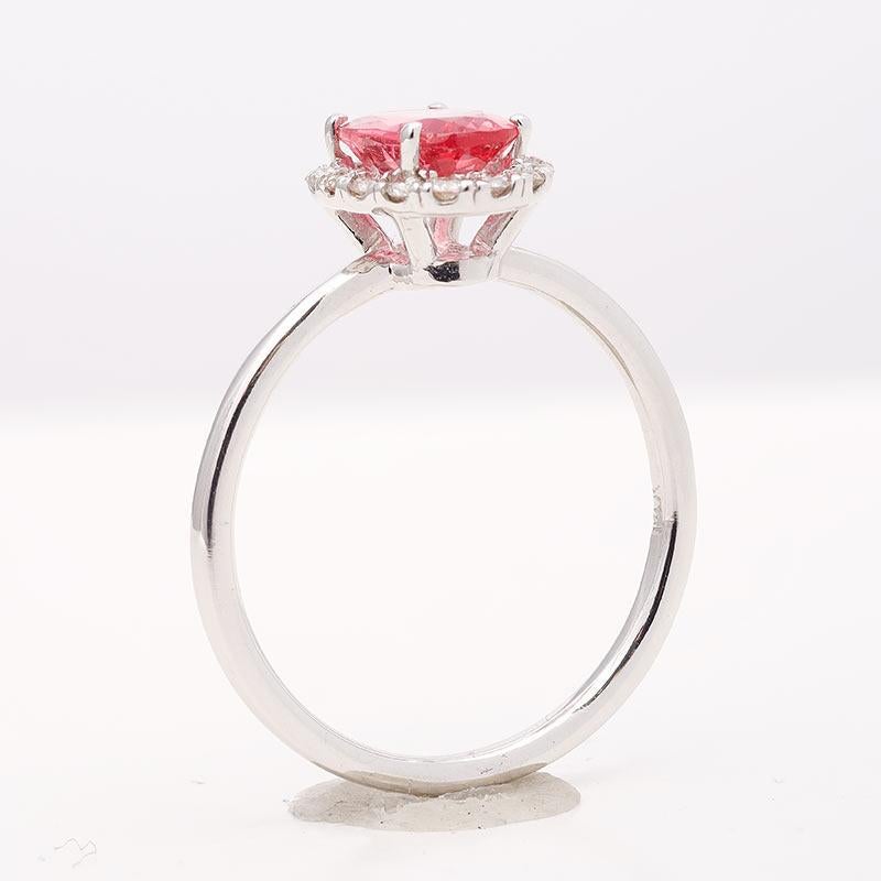 Simple and sparkling, this ring has a neon Spinel placed at its center with diamonds that appear to be a radiating ring surrounding the gem. Mined in Tanzania, this Spinel with good clarity and an even tone is a rare sight. A simple yet chic option,
