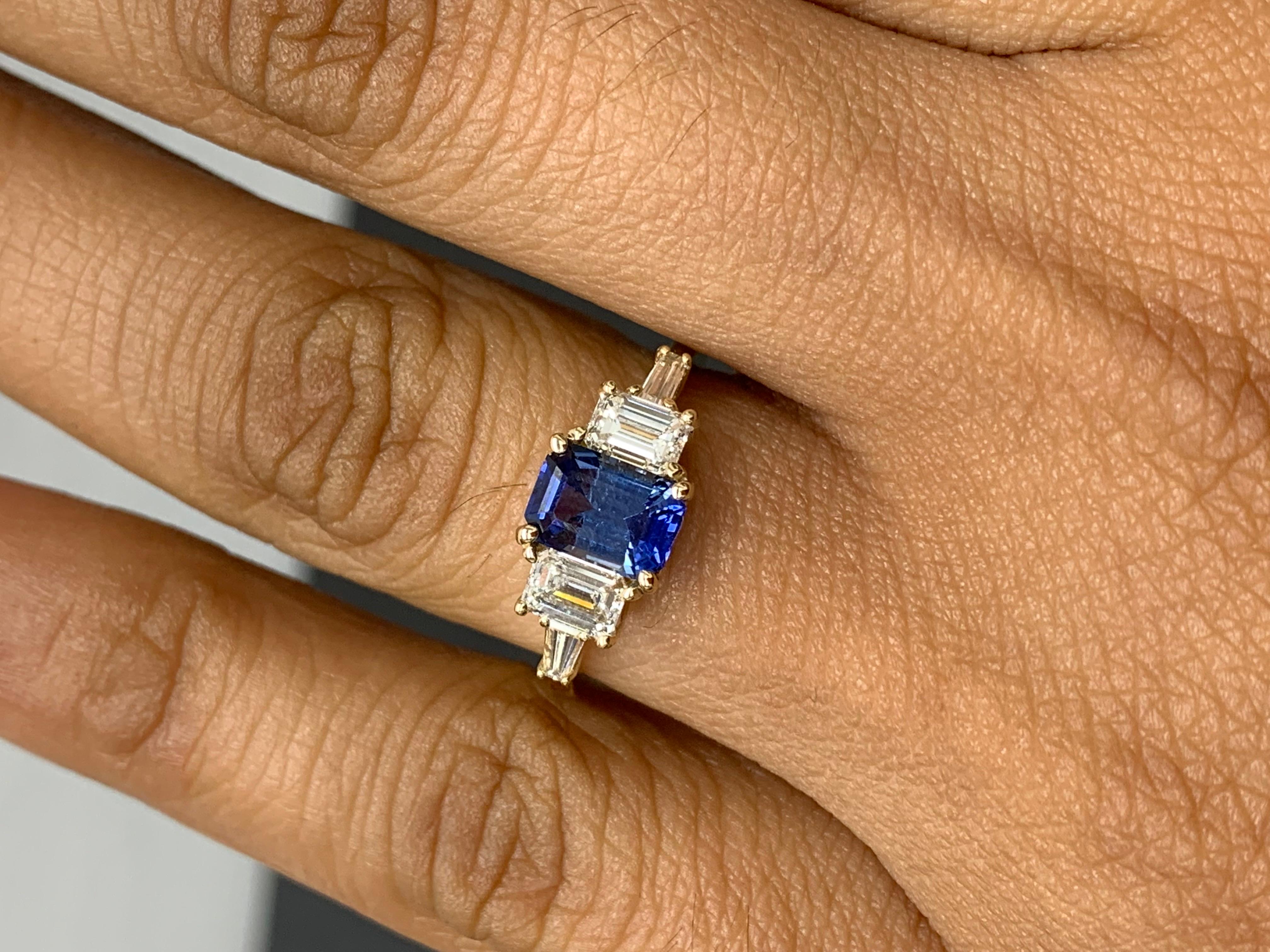 Cette magnifique bague est ornée d'un saphir bleu royal de taille émeraude d'un poids de 1,12 carat. La pierre centrale est flanquée de deux diamants de taille émeraude pesant 0,64 carat et de deux diamants baguette de chaque côté pesant 0,21 carat