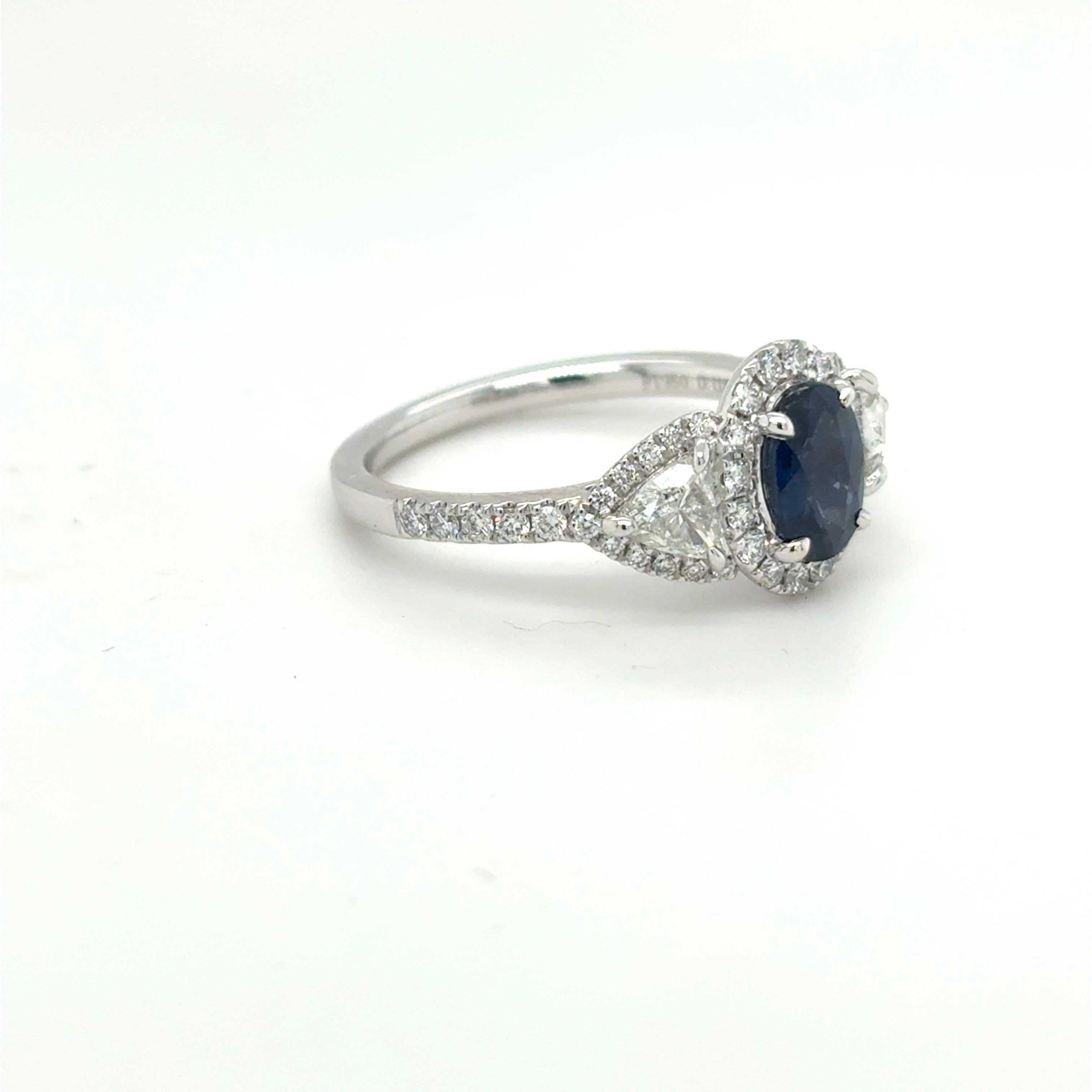 A captivating 1.12 carat oval cut yellow sapphire takes center stage in this exquisite platinum ring, encircled by a dazzling halo of 0.41 carat fine white diamonds. Flanked by two perfectly matched 0.55 carat trillion cut diamonds on either side,