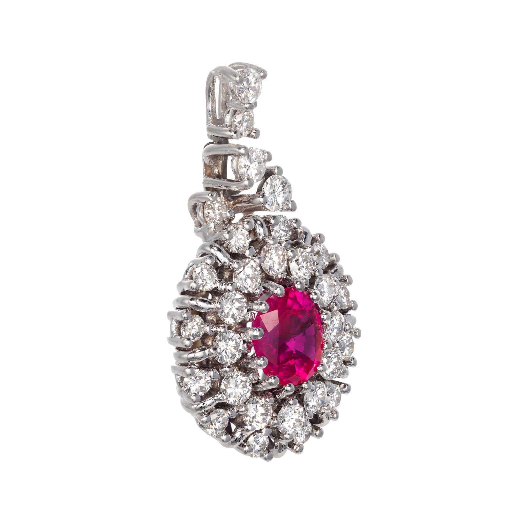 18k white gold vintage style Ruby and Diamond pendant. Oval Ruby sits center surrounded by 2 rows of round brilliant cut Diamonds with additional accent Diamonds hiding the bale.

1 oval pinkish red Ruby, approx. total weight 1.12cts, 7.28 x 6.23 x