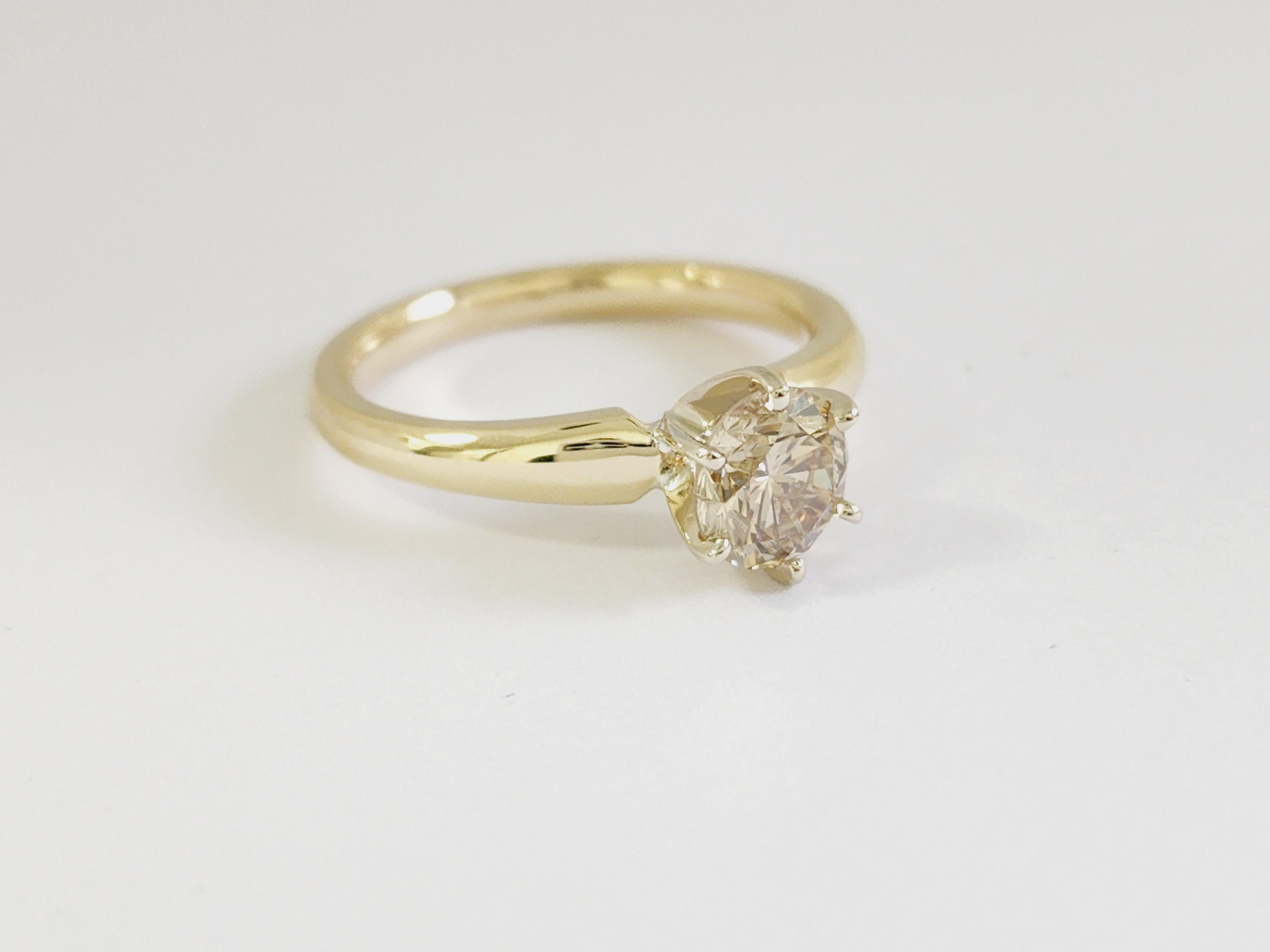1.12 Carats round diamond set on a 6 prong Yellow gold 14 Karat solitaire Ring. 
Color Fancy Light Brownish Yellow, Clarity I1
Ring Size 7 can be resized