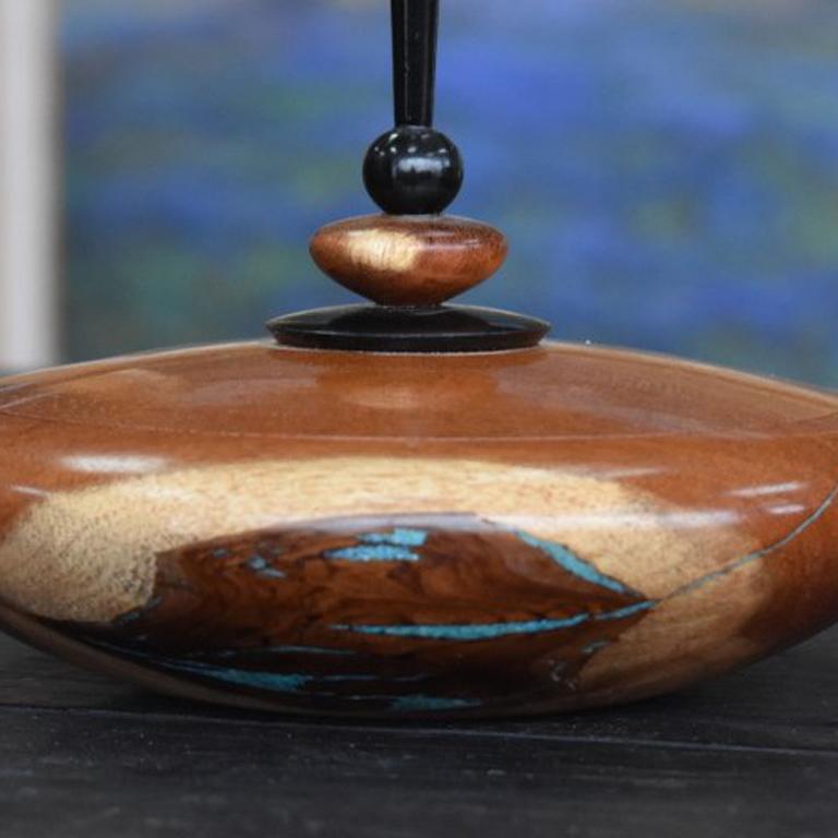 Carmie  (1959-)  Mesquite Lidded Finial Box w/angled tip  Height 5.5'' Diameter 6.5''
Bio
Carmie (1959-) 
Wood Turner Carmie K. Acosta was born and raised in San Antonio. By day he works as a synthetic organic chemist specializing in steroid
