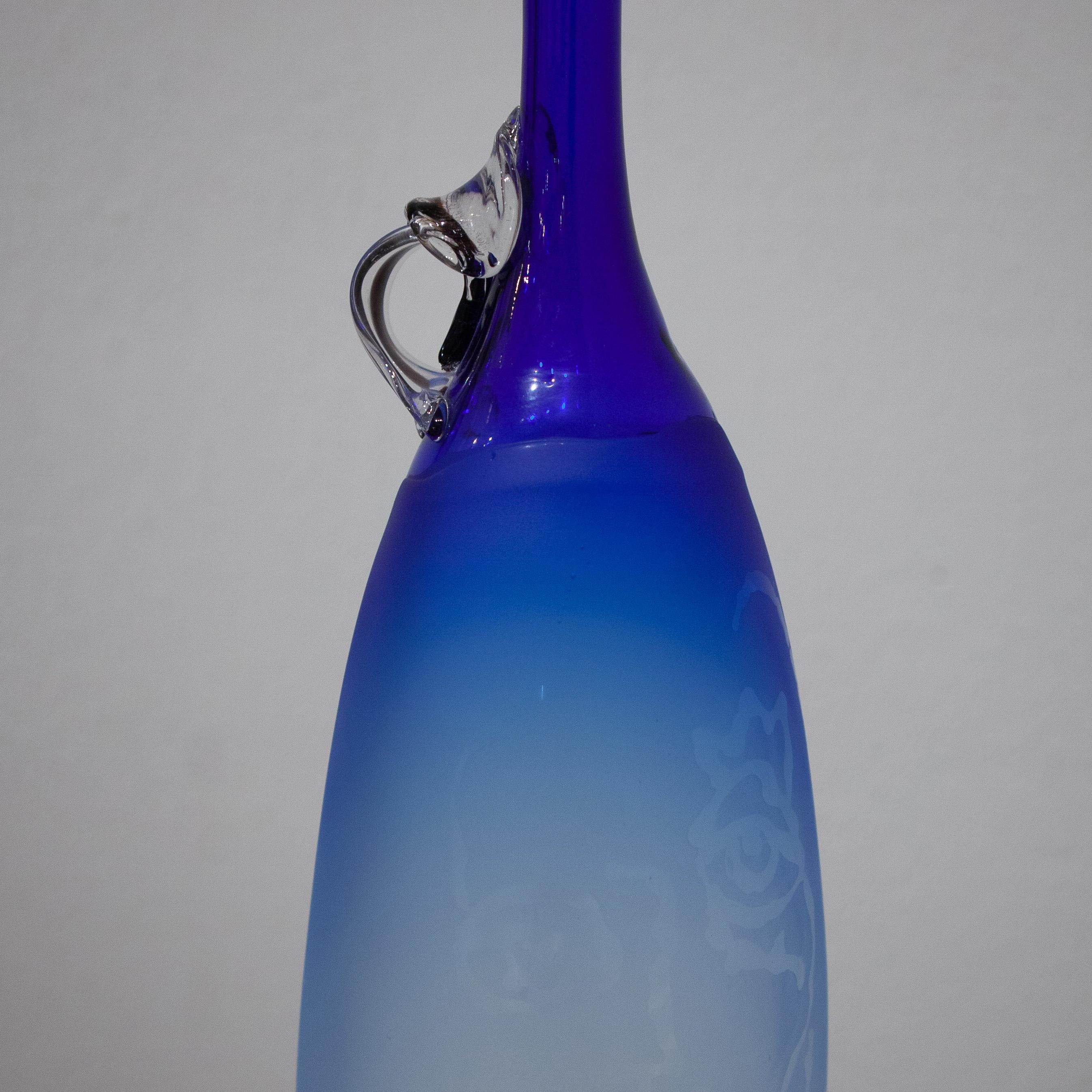 This vase was colored with Cobalt Glass. This technical form was then sandblasted with Robert G. Burch’s drawing of his muse. The drawings really pop with sunlight.
