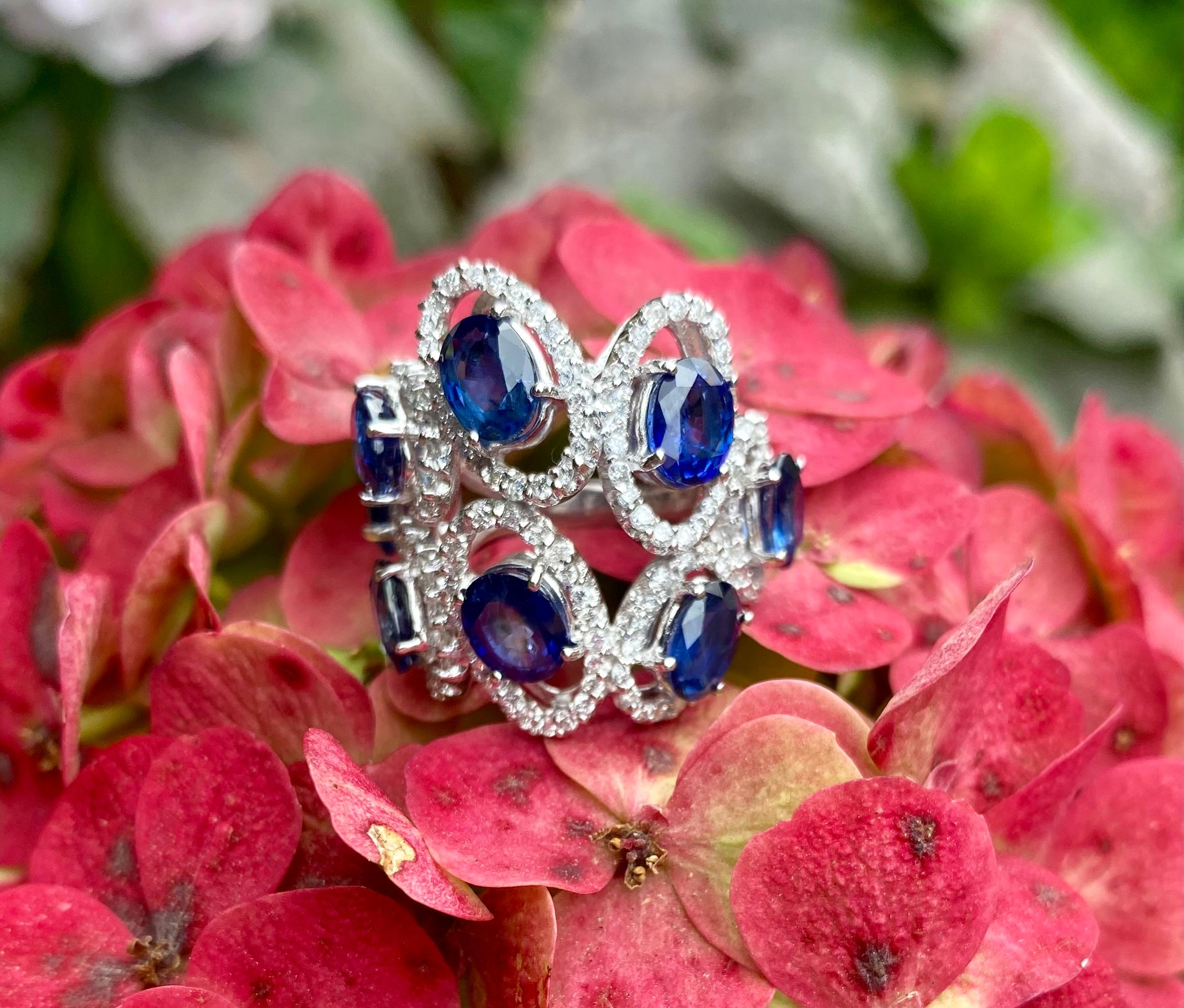 Exquisite and very striking, 18 karat white gold estate sapphire and diamond cocktail ring features 8 oval shaped full cut faceted natural blue sapphires, each suspended in a diamond halo, giving them a dreamy floating like affect.

Each blue