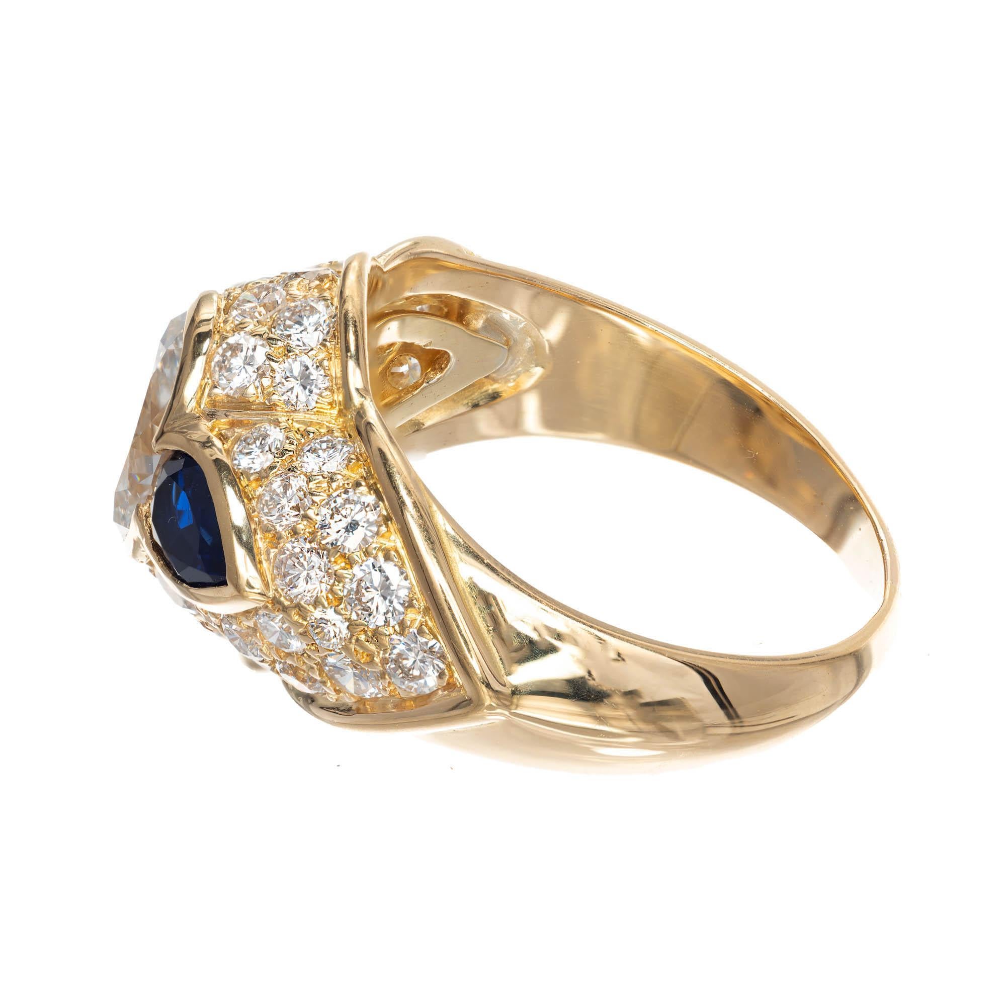 Diamond and sapphire 18k gold engagement ring. Oval cut diamond center stone bezel set and accented by pear shape blue sapphires on each side with extra fine quality round brilliant cut diamonds set all around scalloped design band.

1 oval G VS2