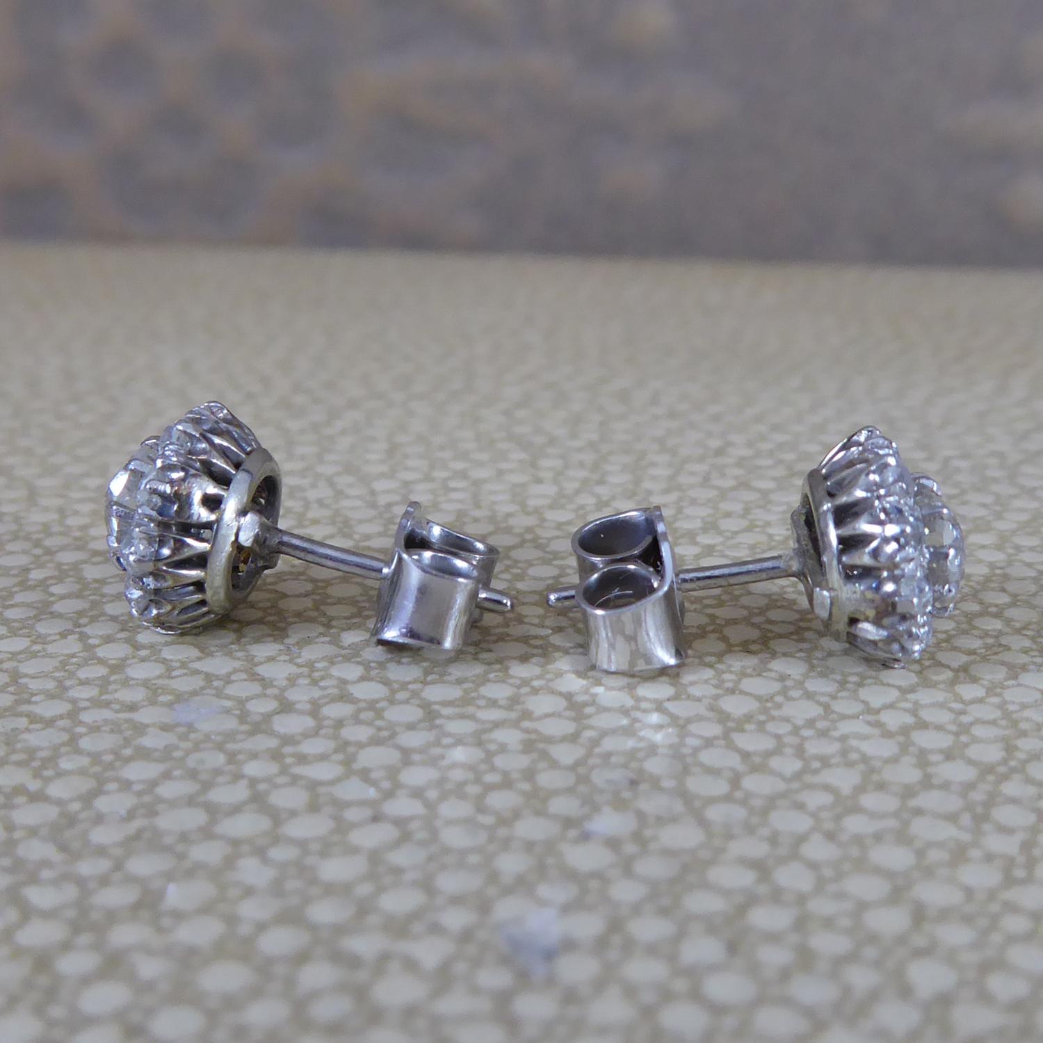 A pair of diamond set cluster stud earrings, each earring centring on a claw set, old European cut diamond, measuring one at 4.36mm x 4.18mm diameter and one at 4.37mm x 4.55mm diameter.  Claw set in white metal to a surround of 10 claw/grain set